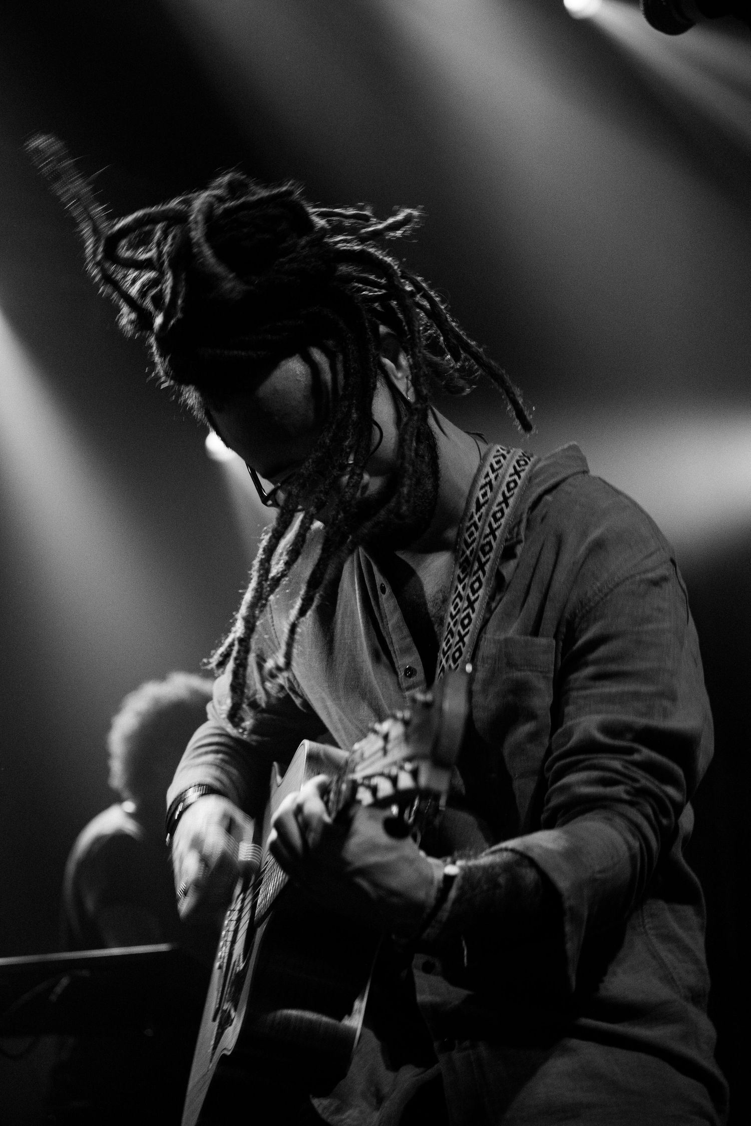 Músico toca guitarra no palco, em fotografia em preto e branco.