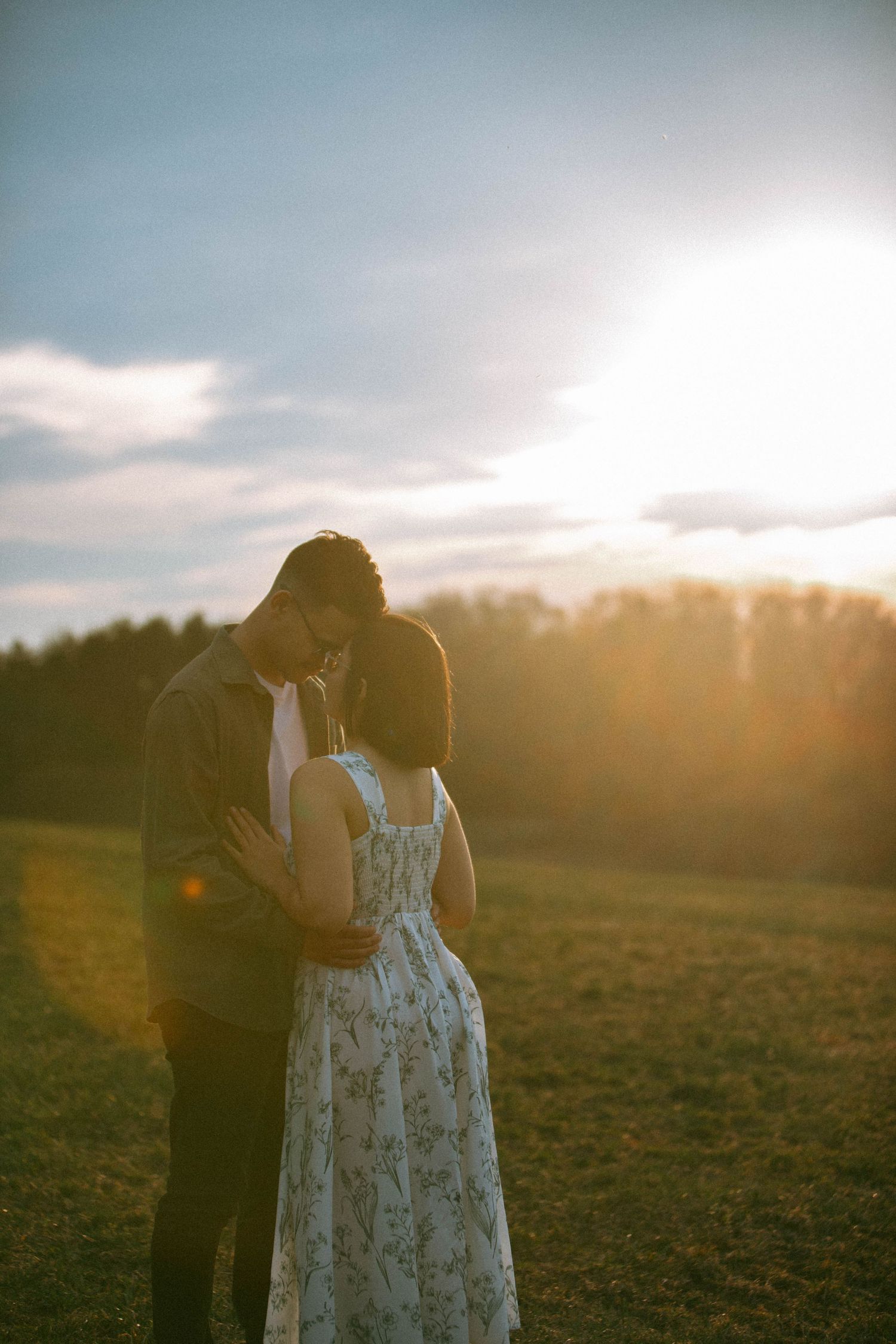 Couple shares an intimate moment during a couples session in a grassy field at golden hour sunset by Lancaster, PA Photographer Debbie