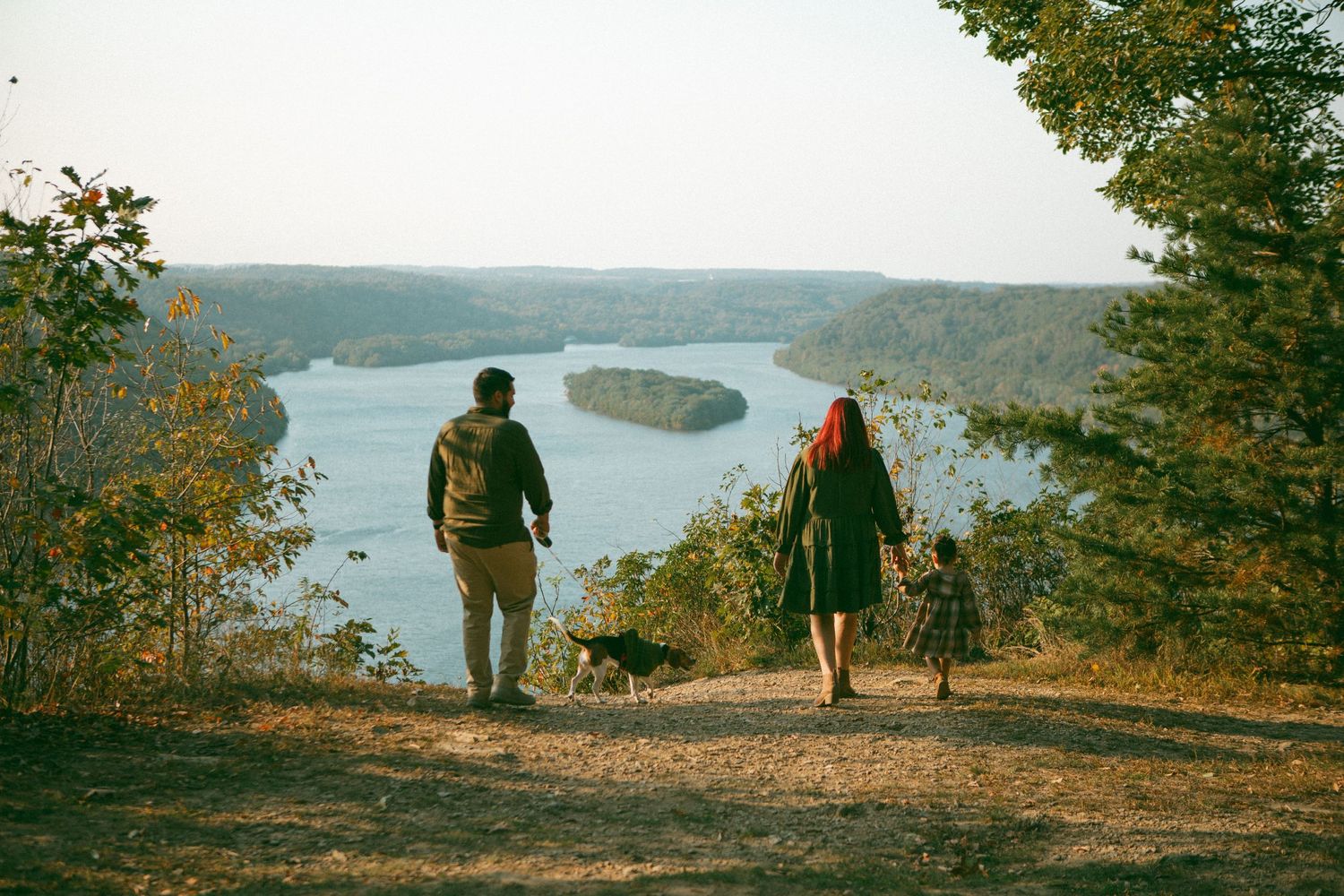 Family walks toward a scenic river overlook, bathed in golden light—capturing adventure and togetherness in a breathtaking outdoor setting.
