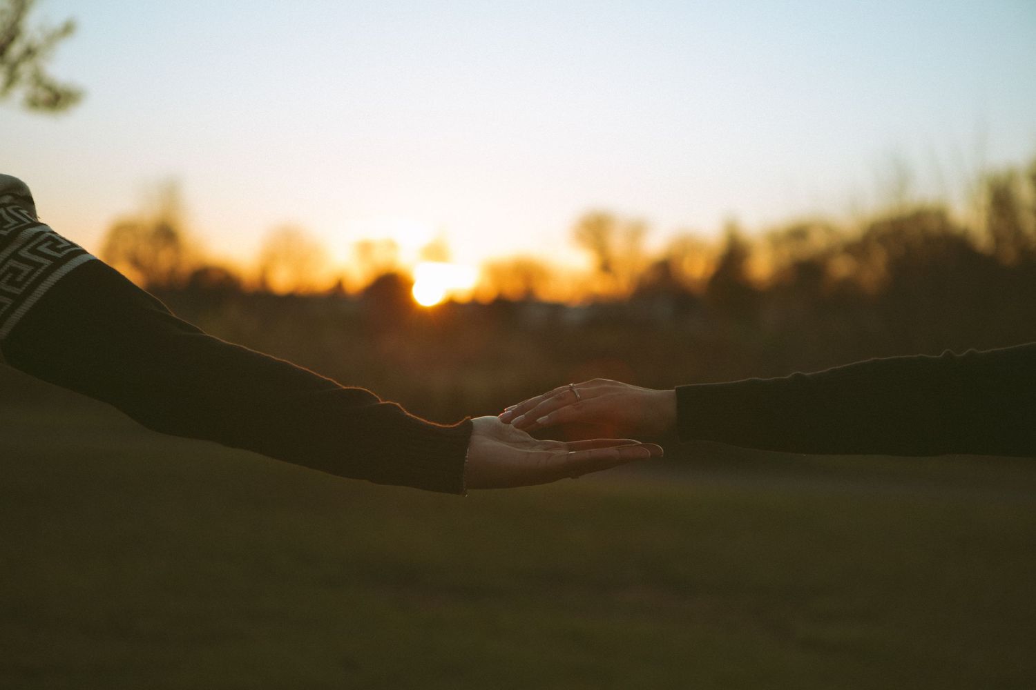 A romantic sunset moment capturing two hands gently touching, symbolizing love, connection, and intimacy against a golden evening sky.