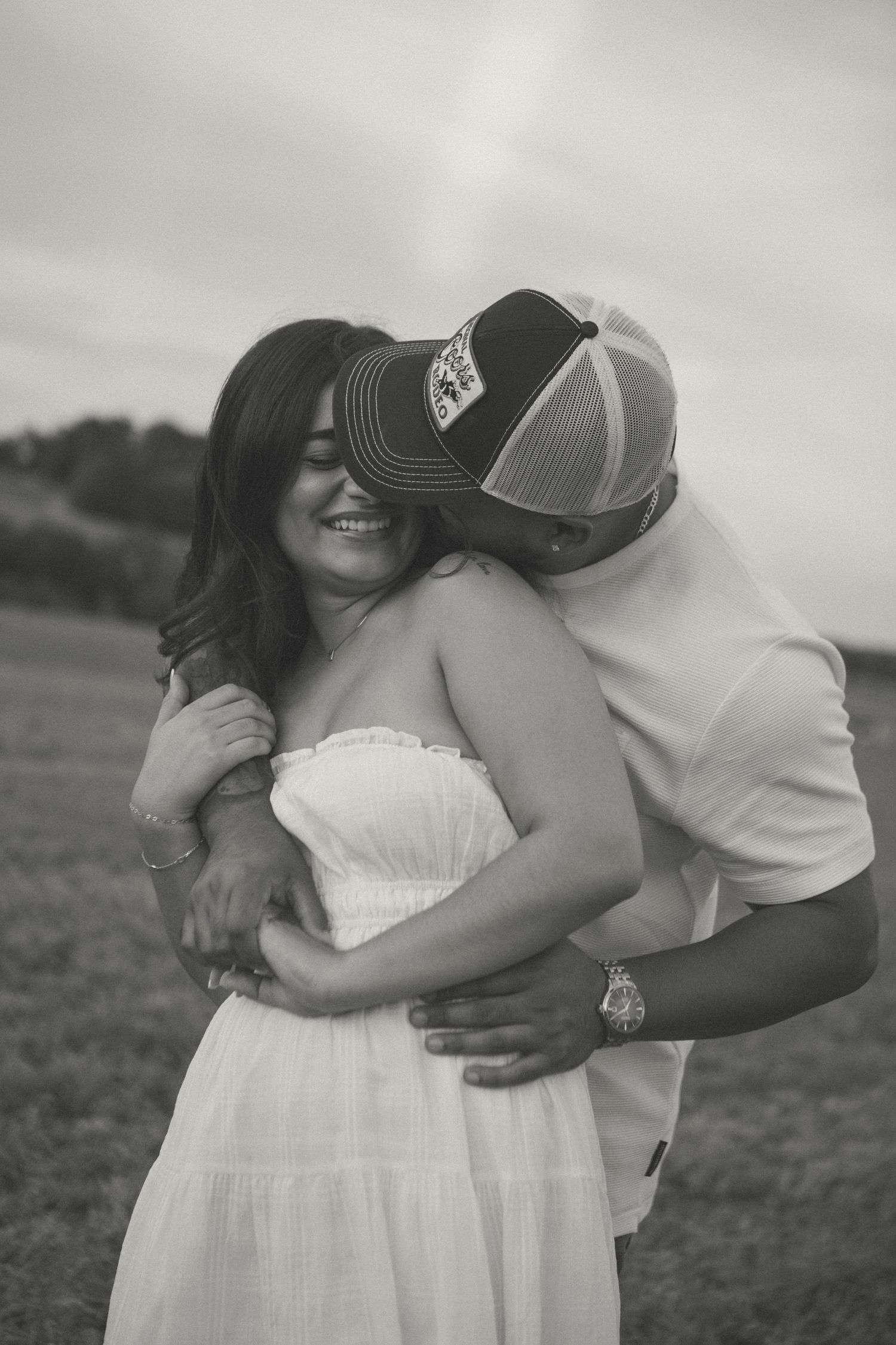 A romantic black and white photo showing close-up embraces between a couple in a field during a storytelling couples session by D'Gallery.