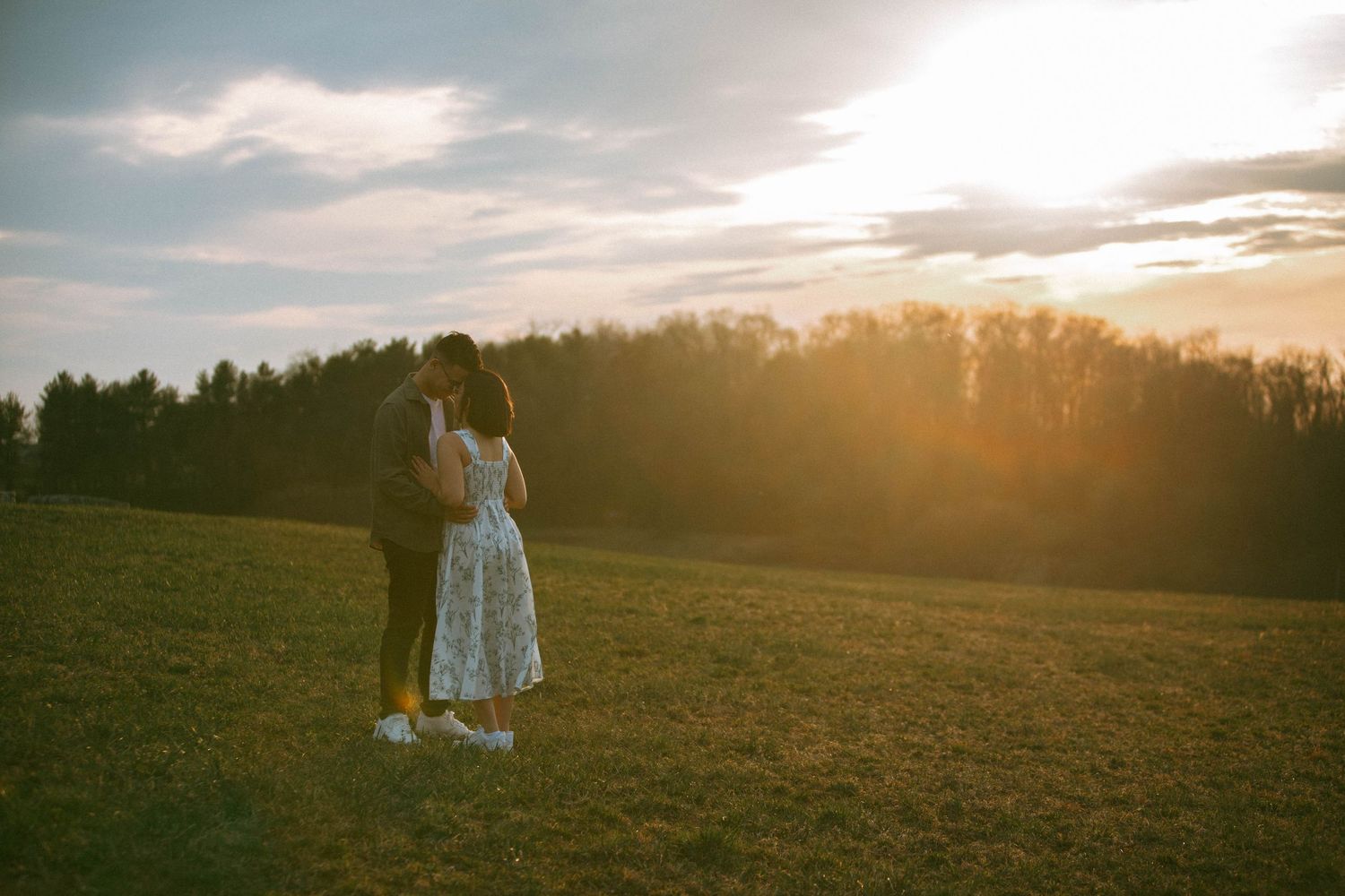 Couple shares an intimate moment during a couples session in a grassy field at golden hour sunset by Lancaster, PA Photographer Debbie