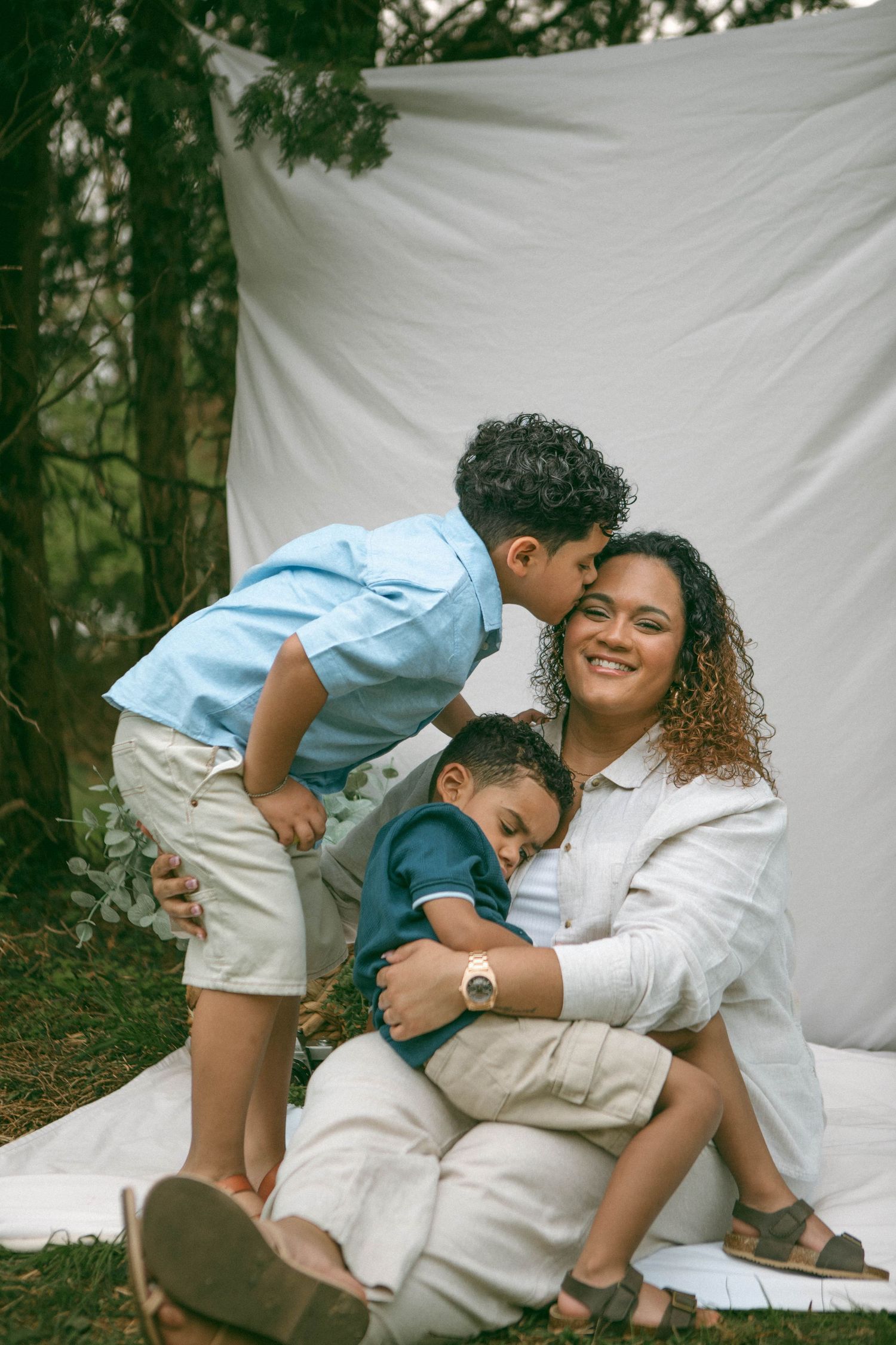 outdoor family moment from Mother's Day mini sessions by Lancaster, PA Photographer on a white blanket against a forest backdrop.