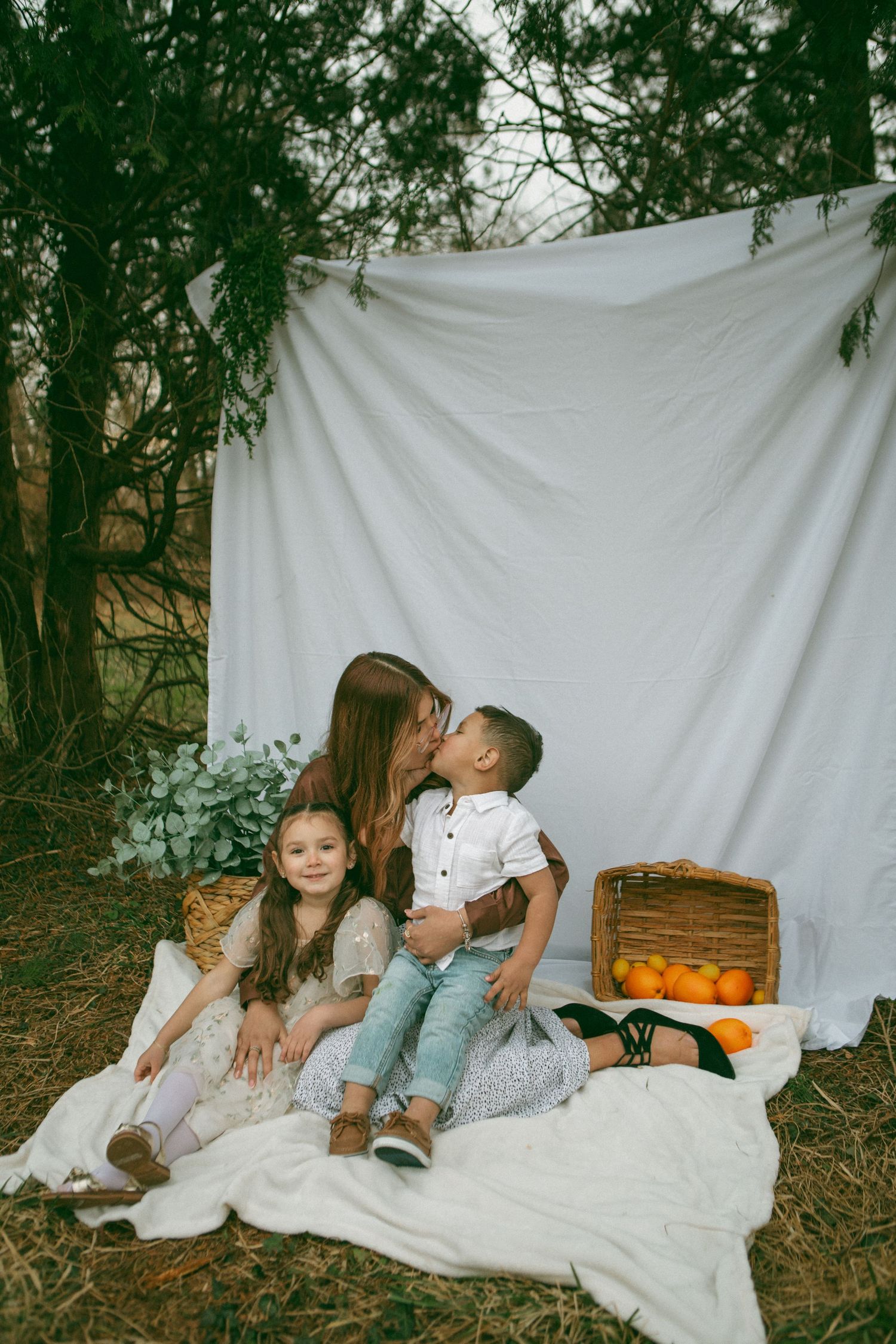 outdoor family moment from Mother's Day mini sessions by Lancaster, PA Photographer on a white blanket against a forest backdrop.