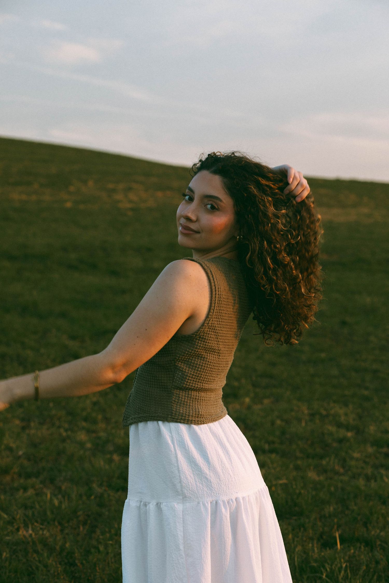A portrait of Debbie, Photographer at D'Gallery Photography, in an outdoor field at sunset.