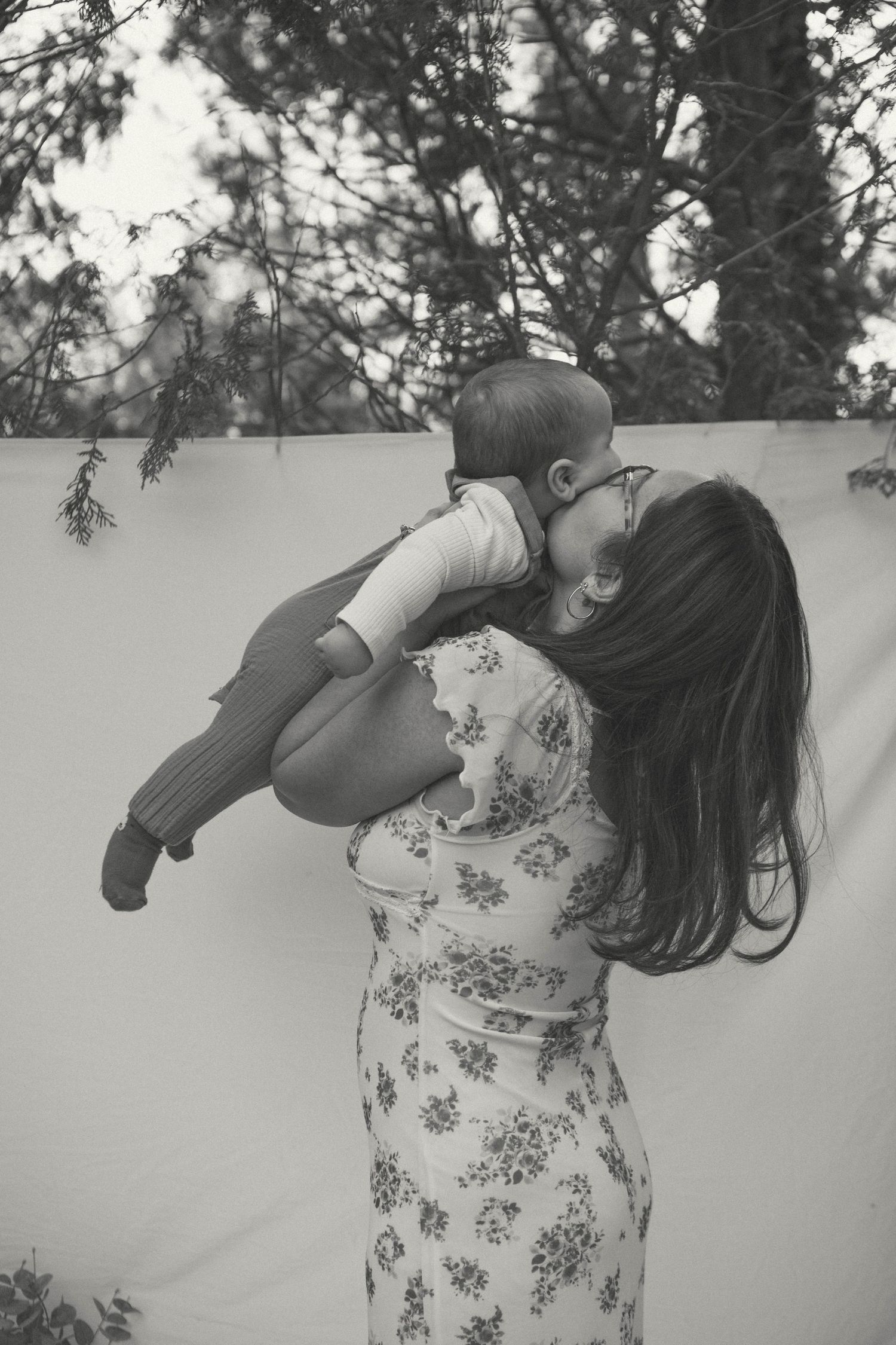 Mother lifts her small child playfully in the air, captured in black and white photography by D'Gallery Photography for Mother's Day minis