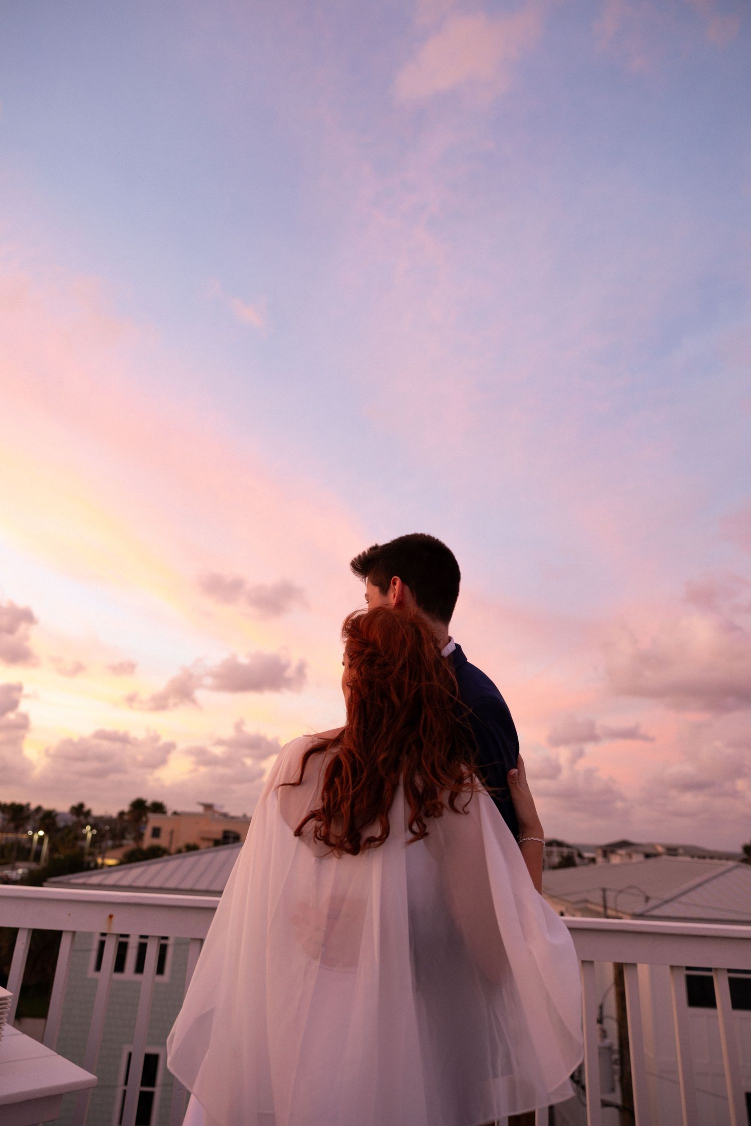 couple embracing while lookin into the purple and pink sunset