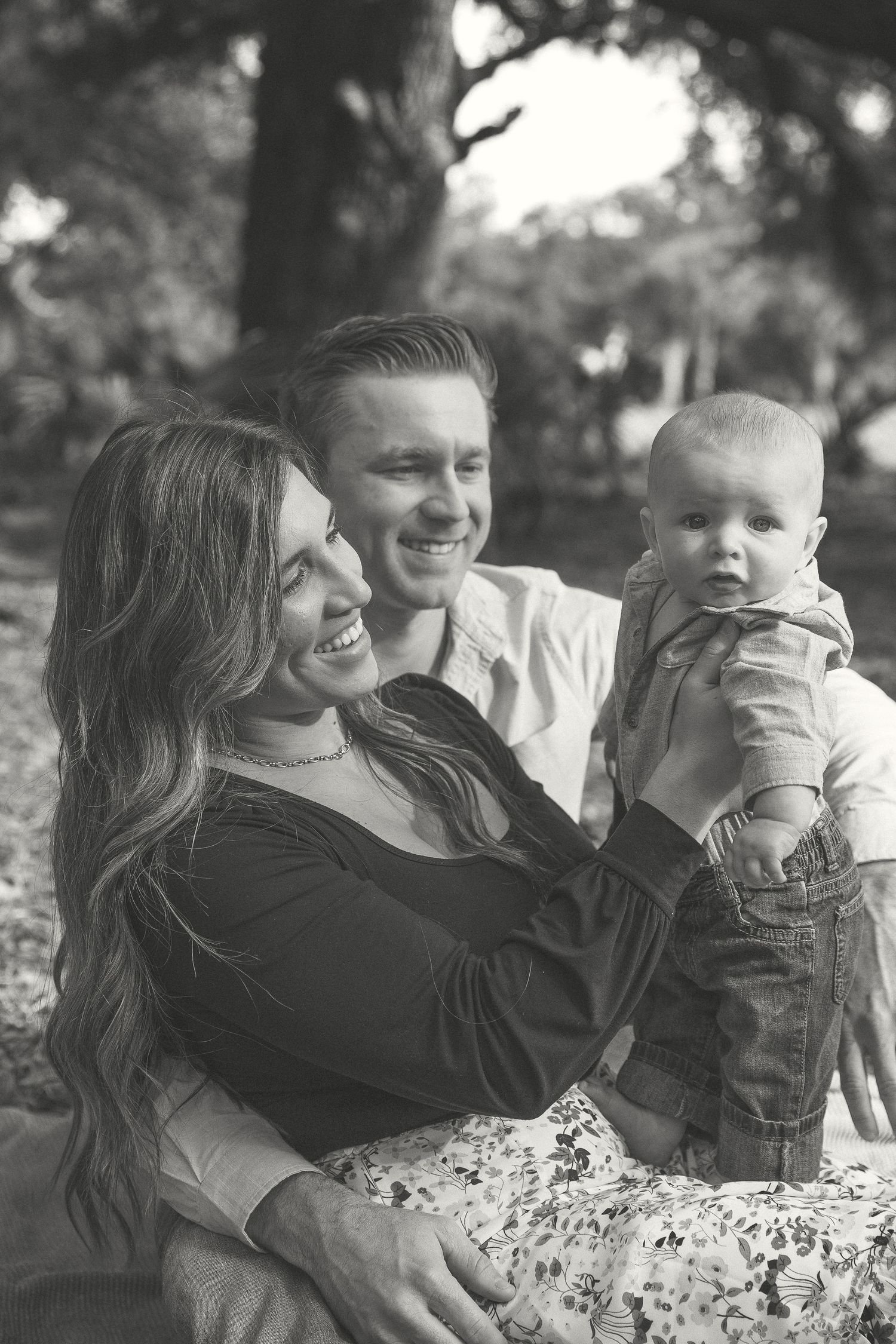A series of black and white photos showing candid family moments outdoors with natural expressions and laughter.