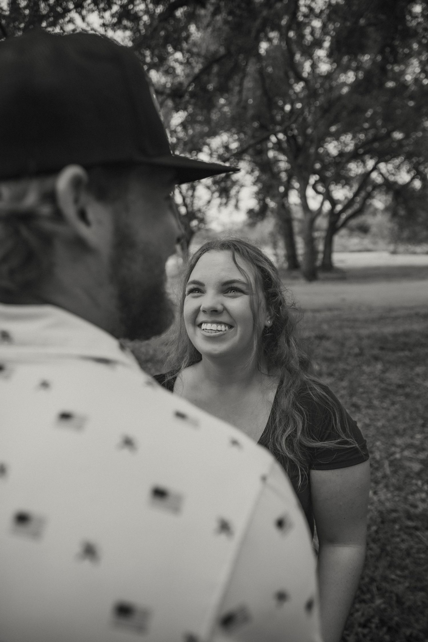 A couple shares a joyful moment together outdoors in black and white photography.