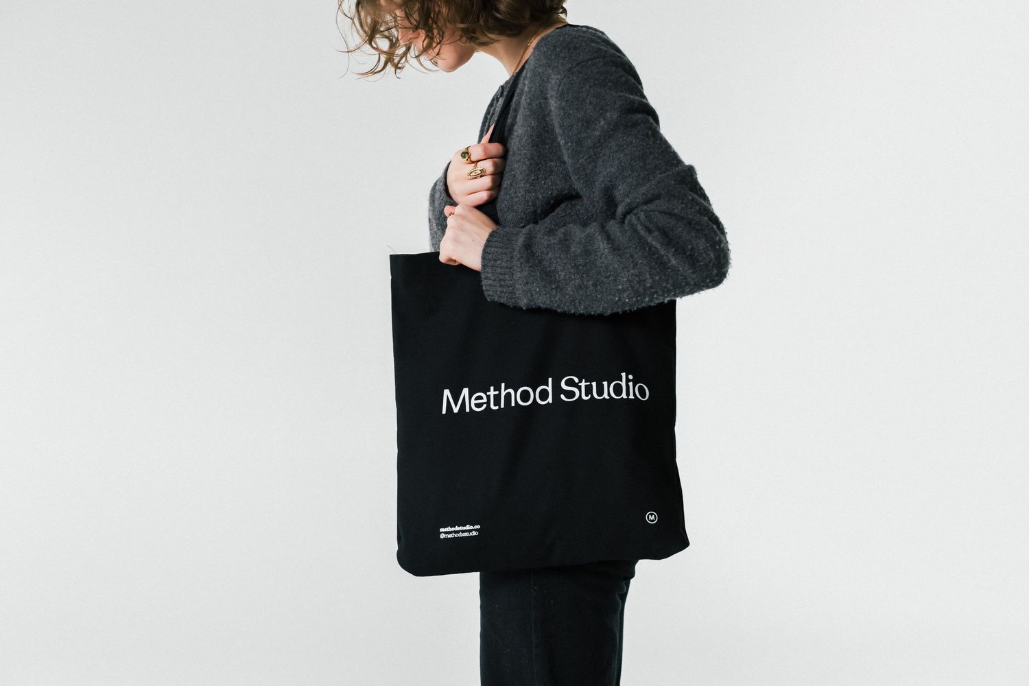 A black canvas tote bag with Method Studio branding shown from multiple angles against a white background.