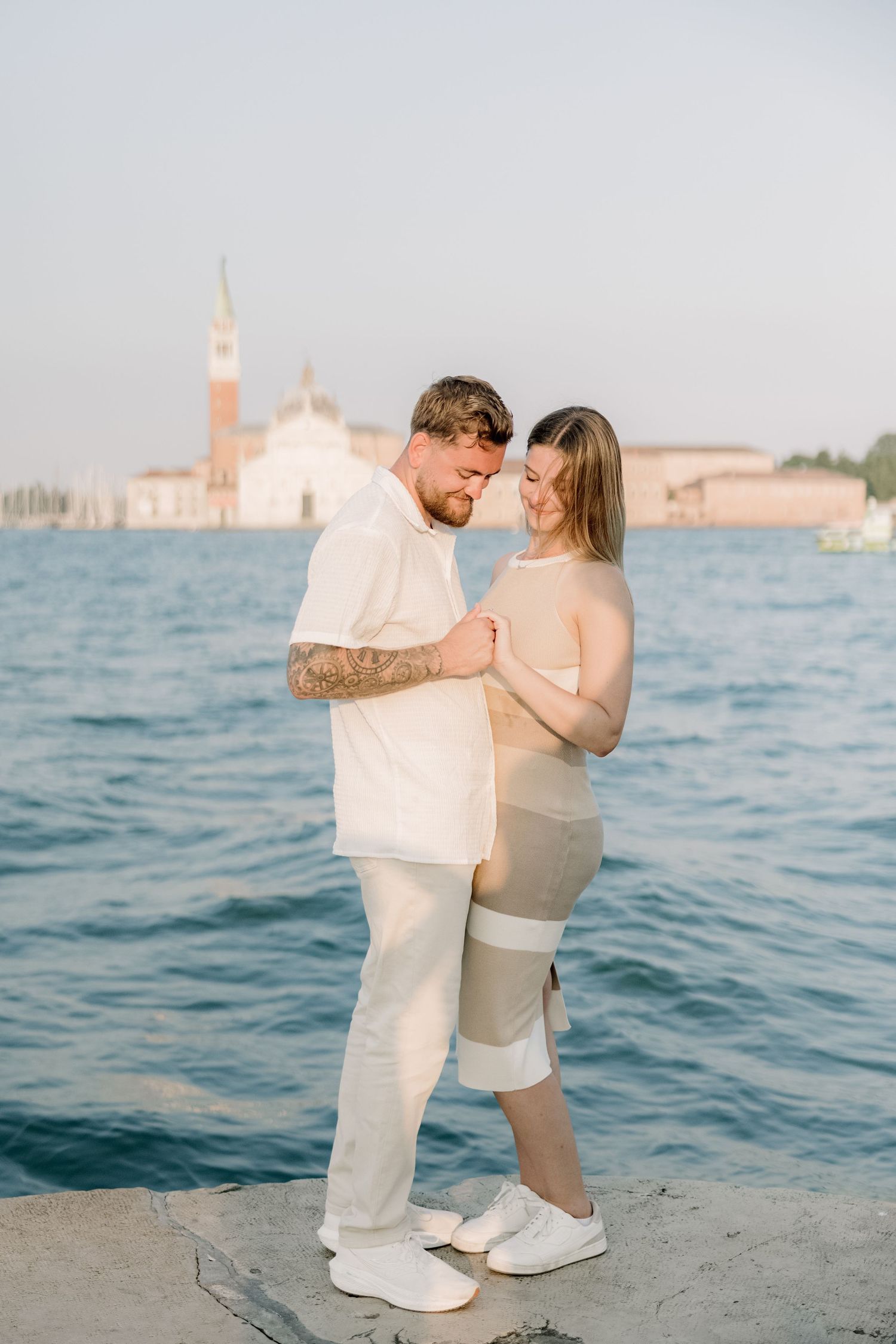 A romantic proposal moment unfolds along the Venice waterfront with the iconic San Giorgio Maggiore church in the background.