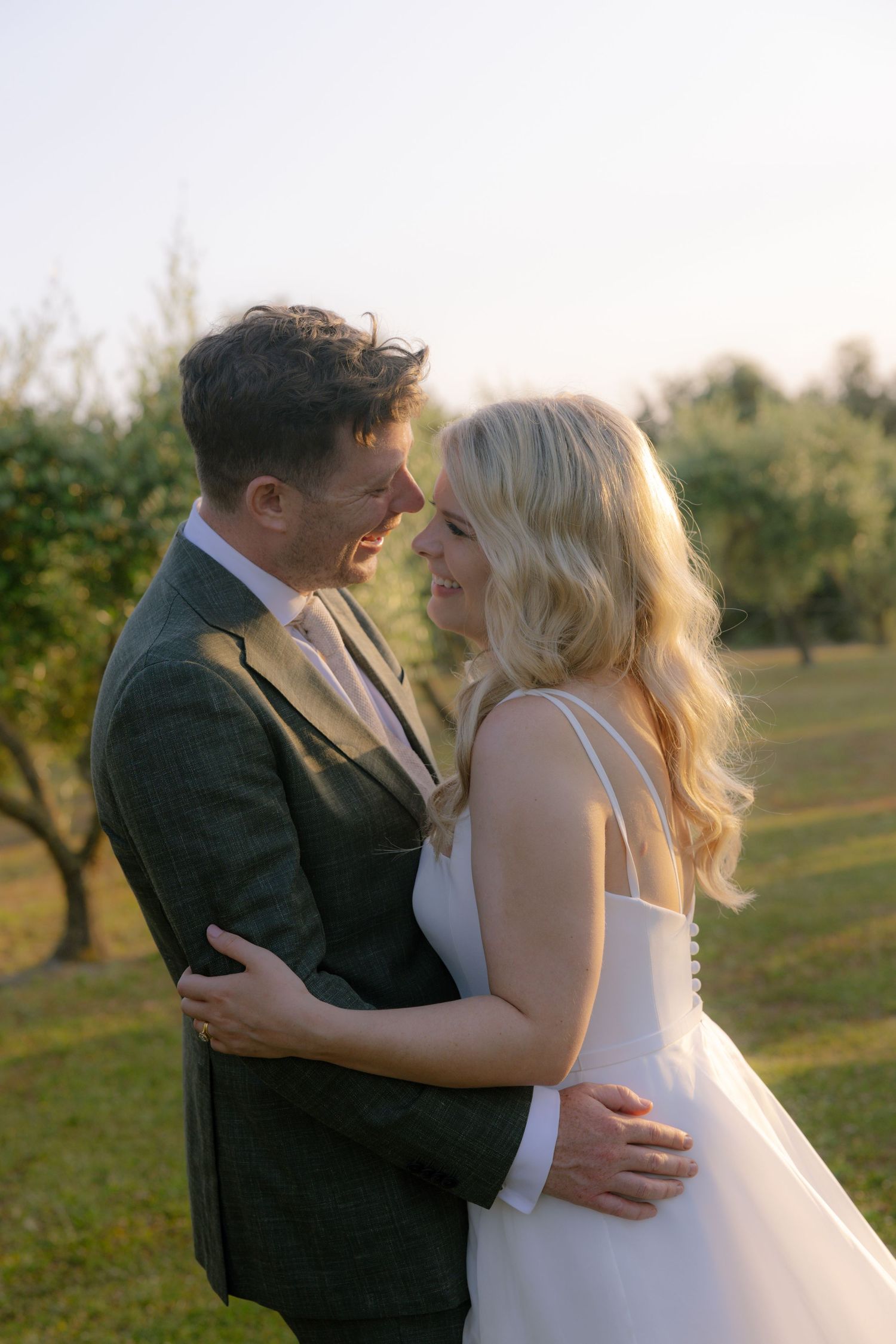 A romantic wedding couple embraces in a golden sunlit field during sunset in Tuscany