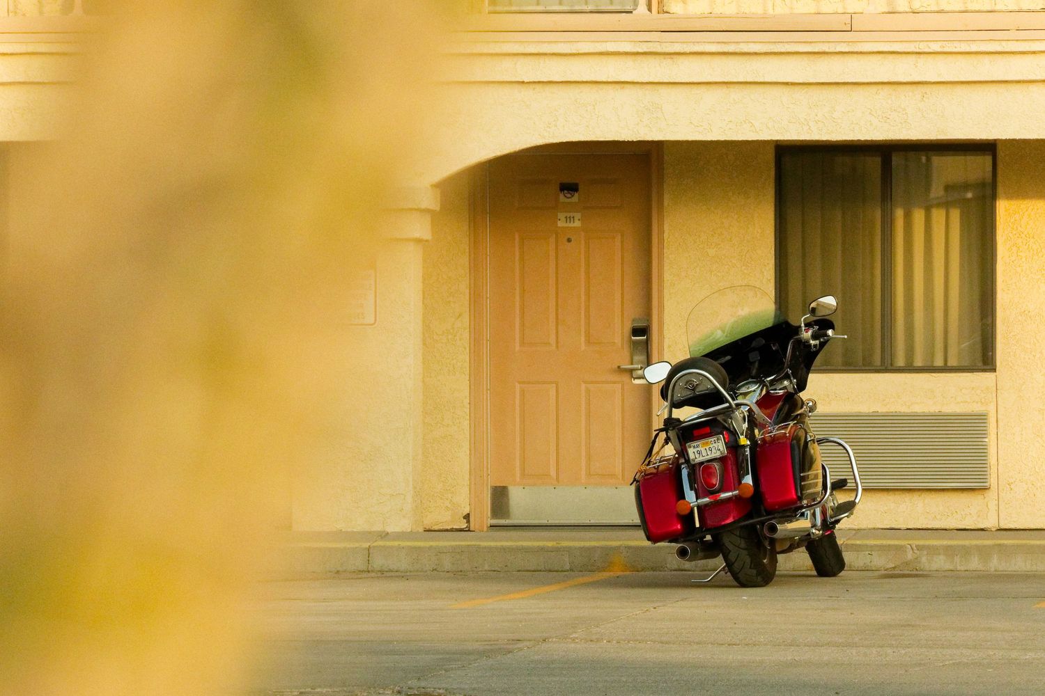 A red motorcycle parked in front of a motel room