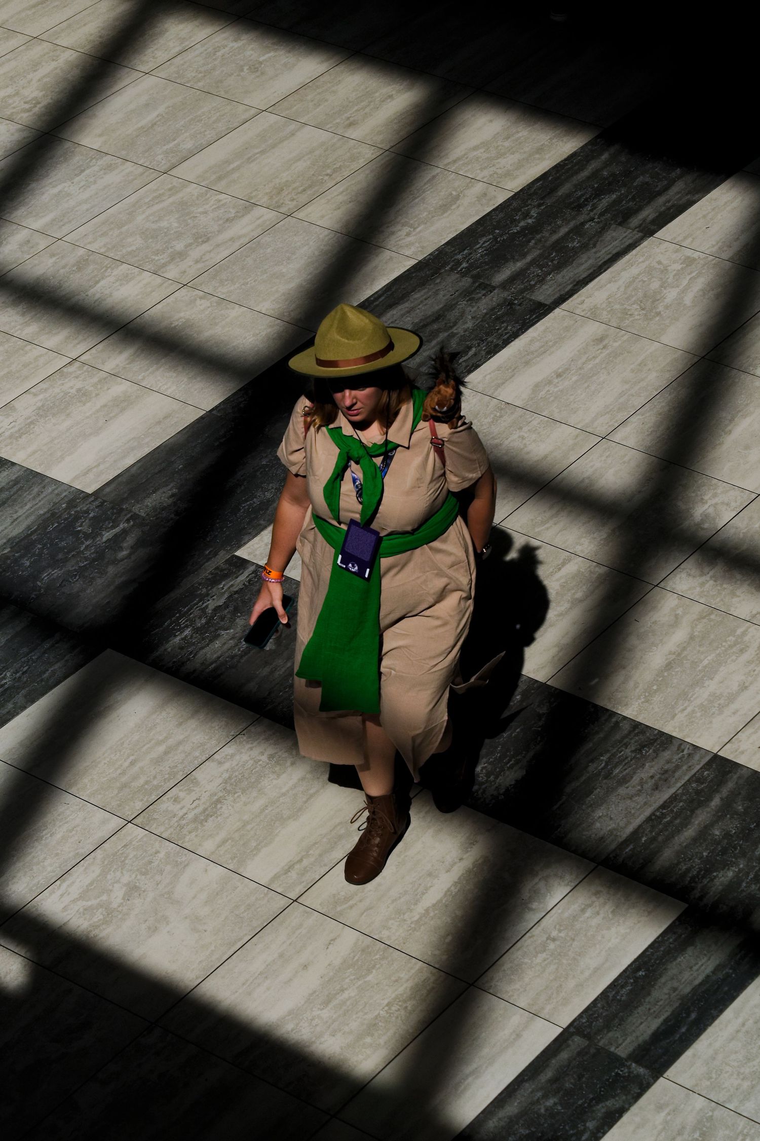 An aerial view of a cosplayer walking across a geometric pattern of shadows on a tiled floor