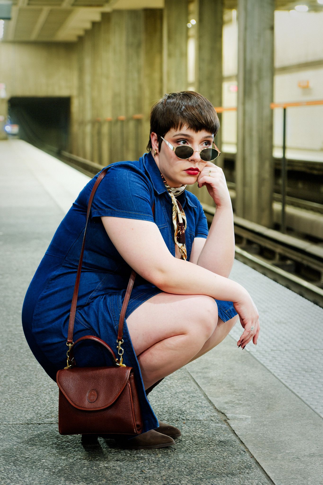 A person in a navy dress and brown leather bag sits on a subway platform in a sequence of similar poses.