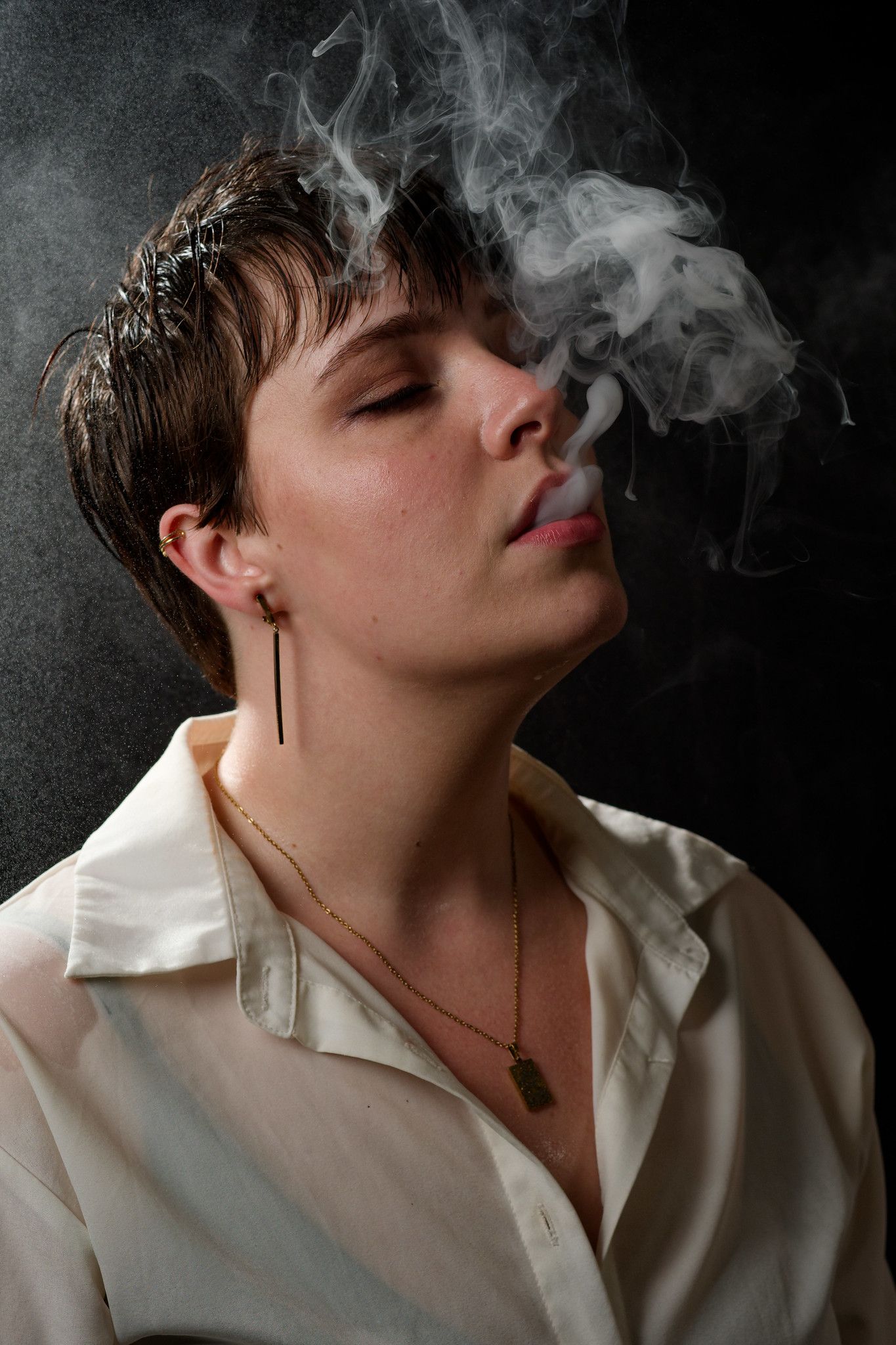 Artistic portrait series showing smoke rising from a person wearing a white shirt against a dark background.