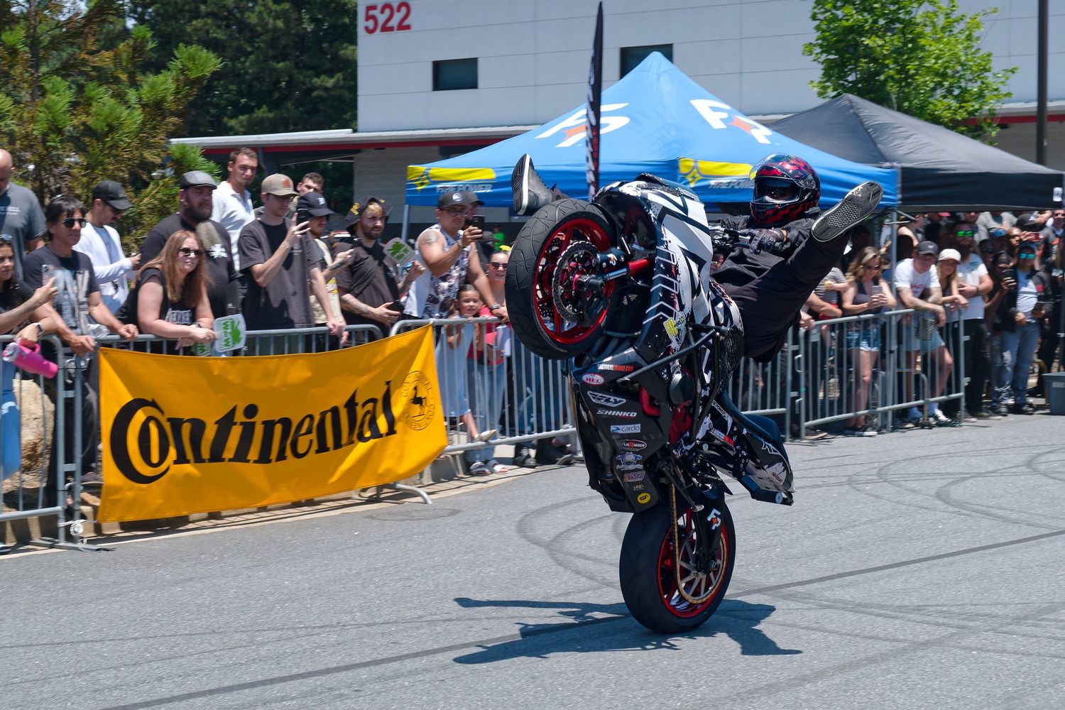 A motorcycle rider performs a wheelie in front of spectators