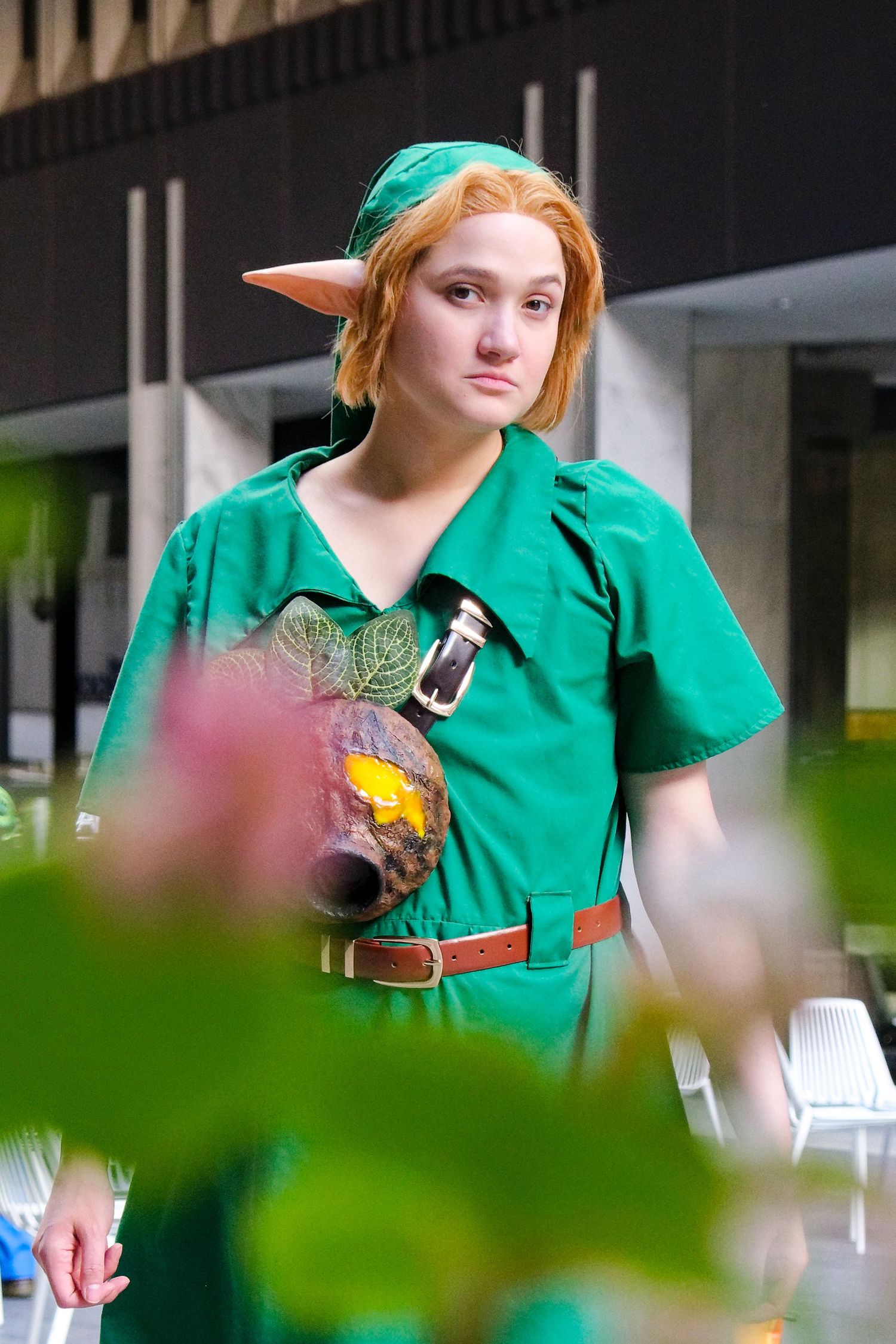 A cosplayer dressed in a green tunic and pointed ears poses in costume