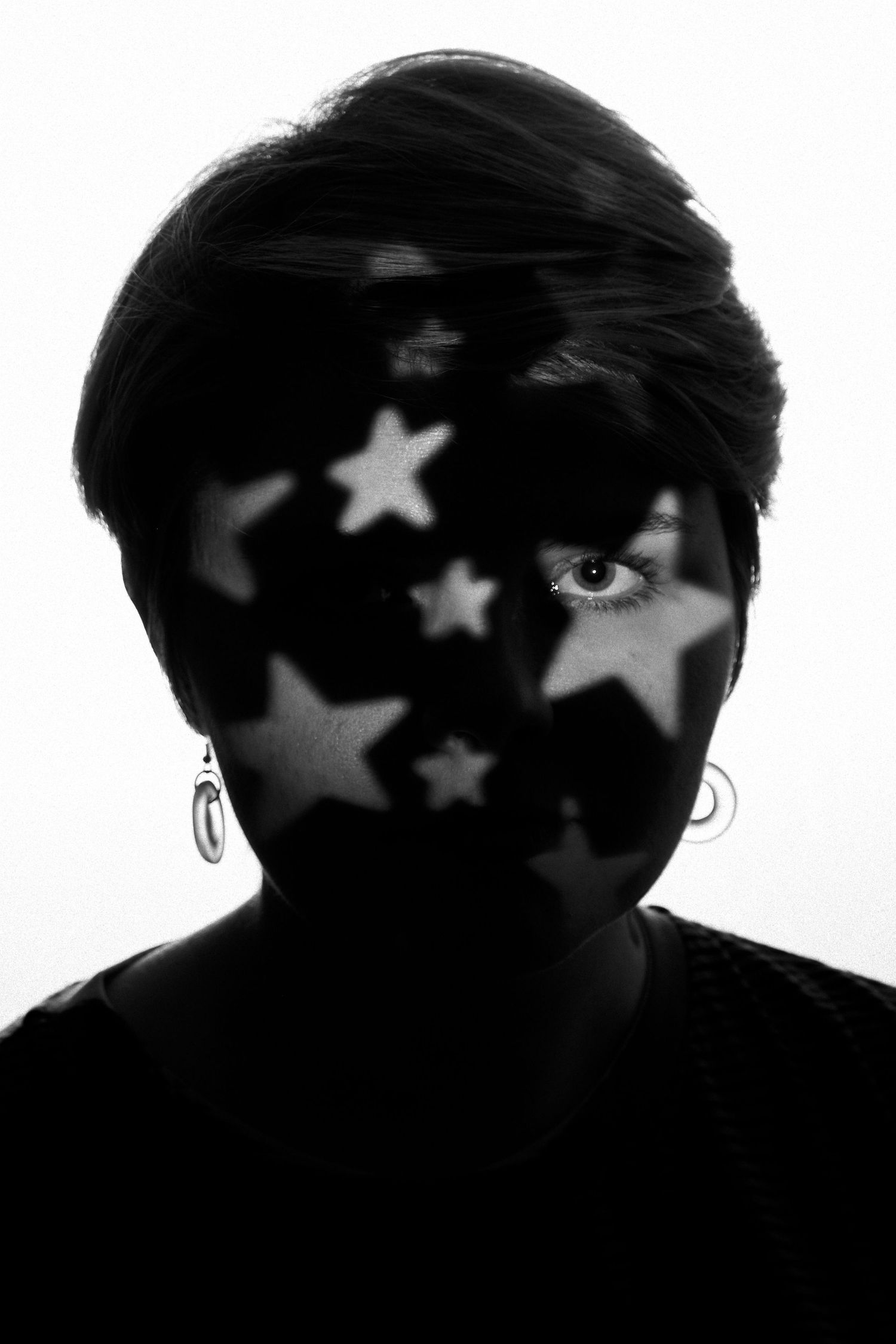 A figure in silhouette with star shaped light cast across her face