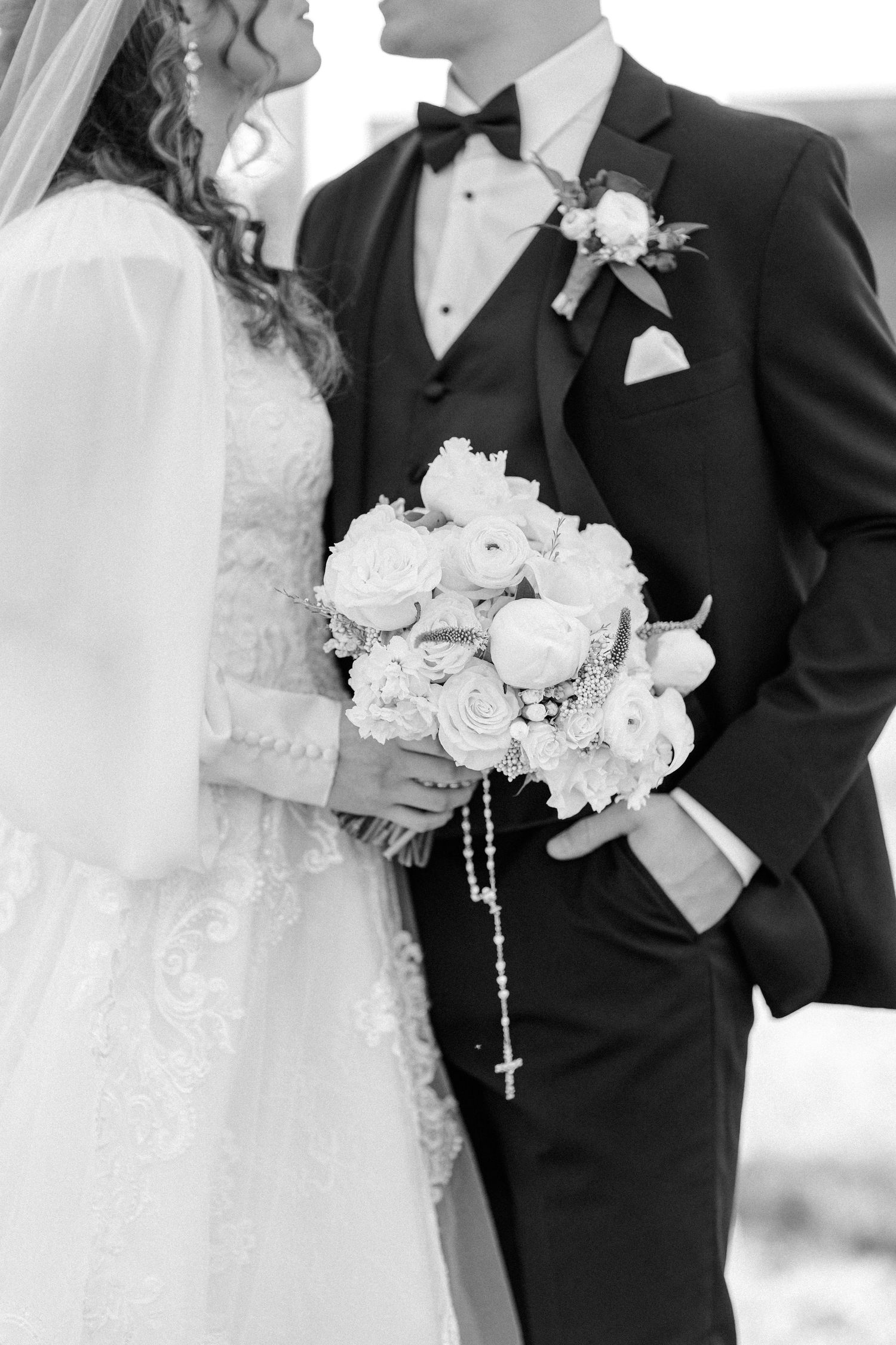 Black and white photo of newlyweds with bouquet and formal attire.