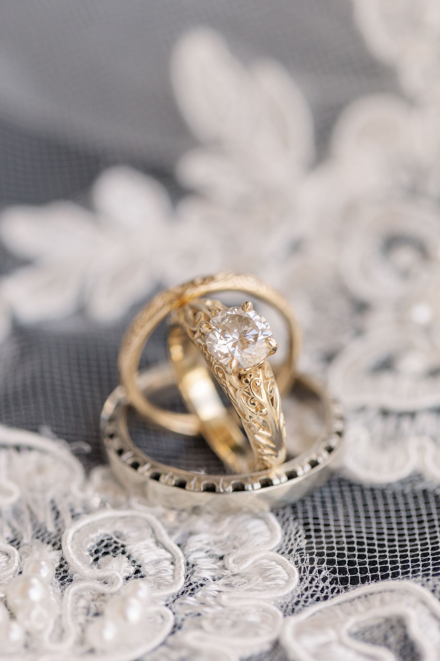 Vintage-style gold diamond engagement ring resting on delicate lace fabric.