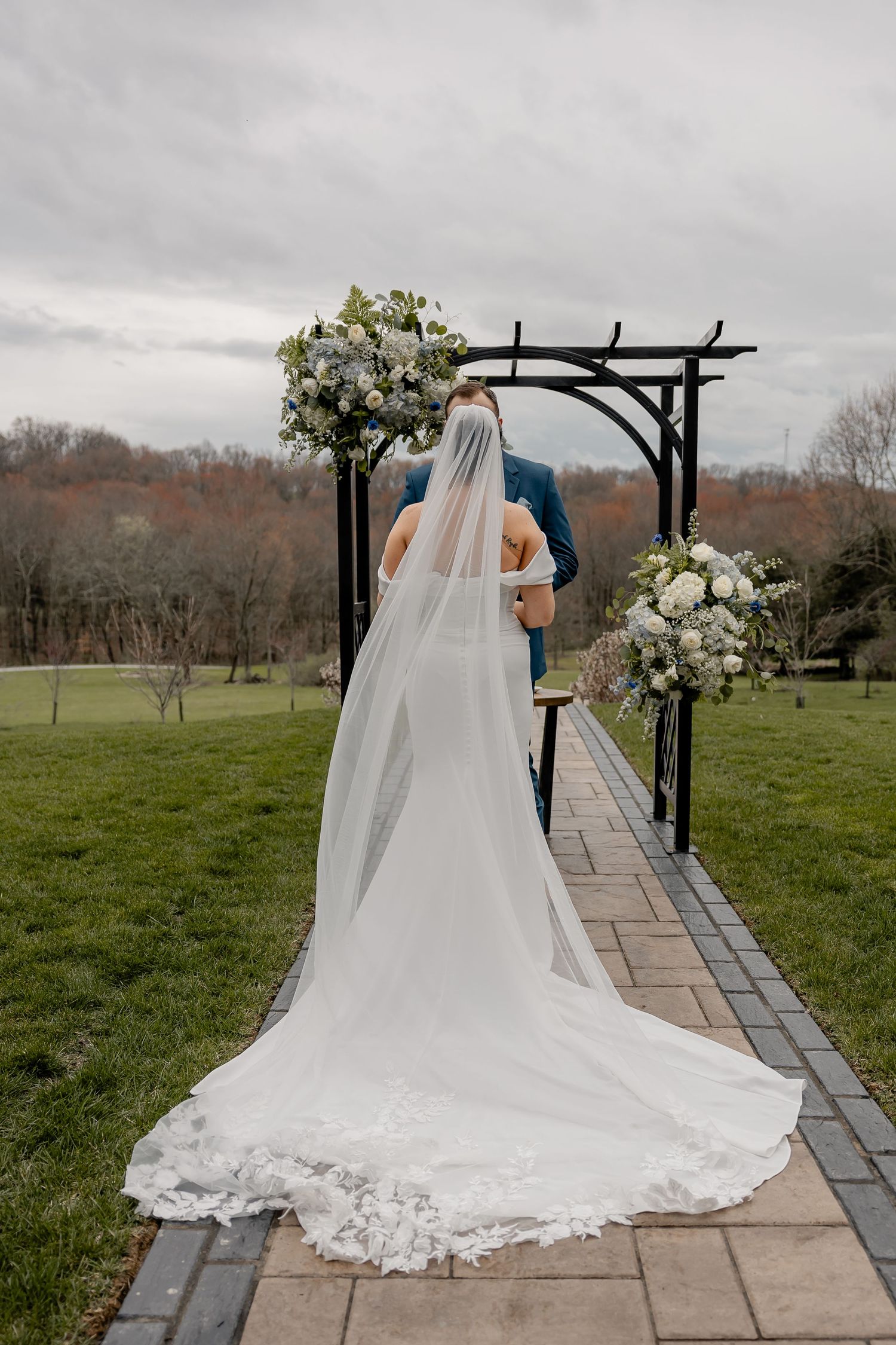 Back of bride’s dress with long train blowing in the wind at outdoor altar – elegant Pittsburgh wedding ceremony moment.