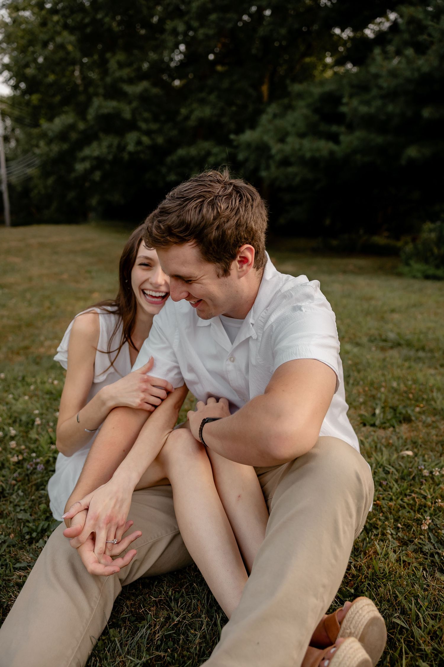 Candid moment of a couple holding hands and laughing while sitting during their Pittsburgh engagement session – natural and joyful couples p