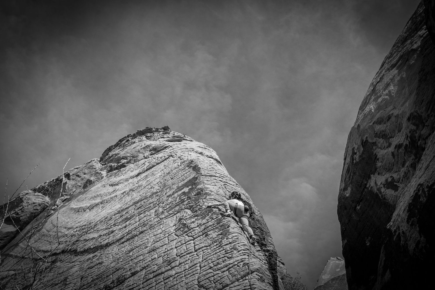 A black and white shot of a girl climbing a steep pitch in Red Rocks, Nevada.