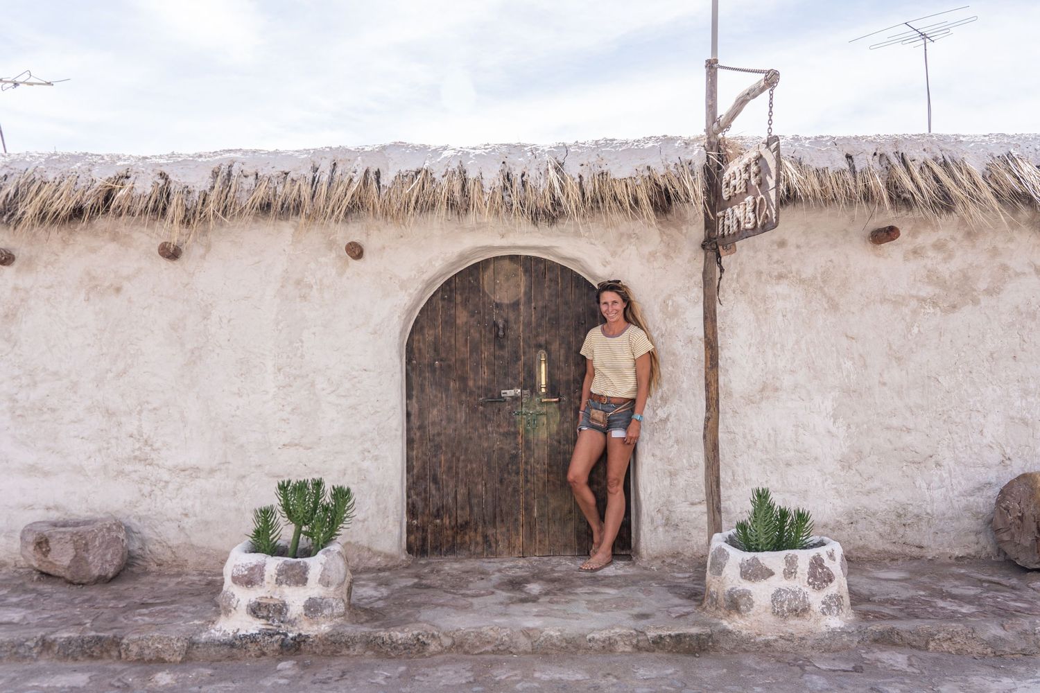 Madison, the photographer from Mad Elopements leans against a white washed cafe in Jujuy, Argentina.