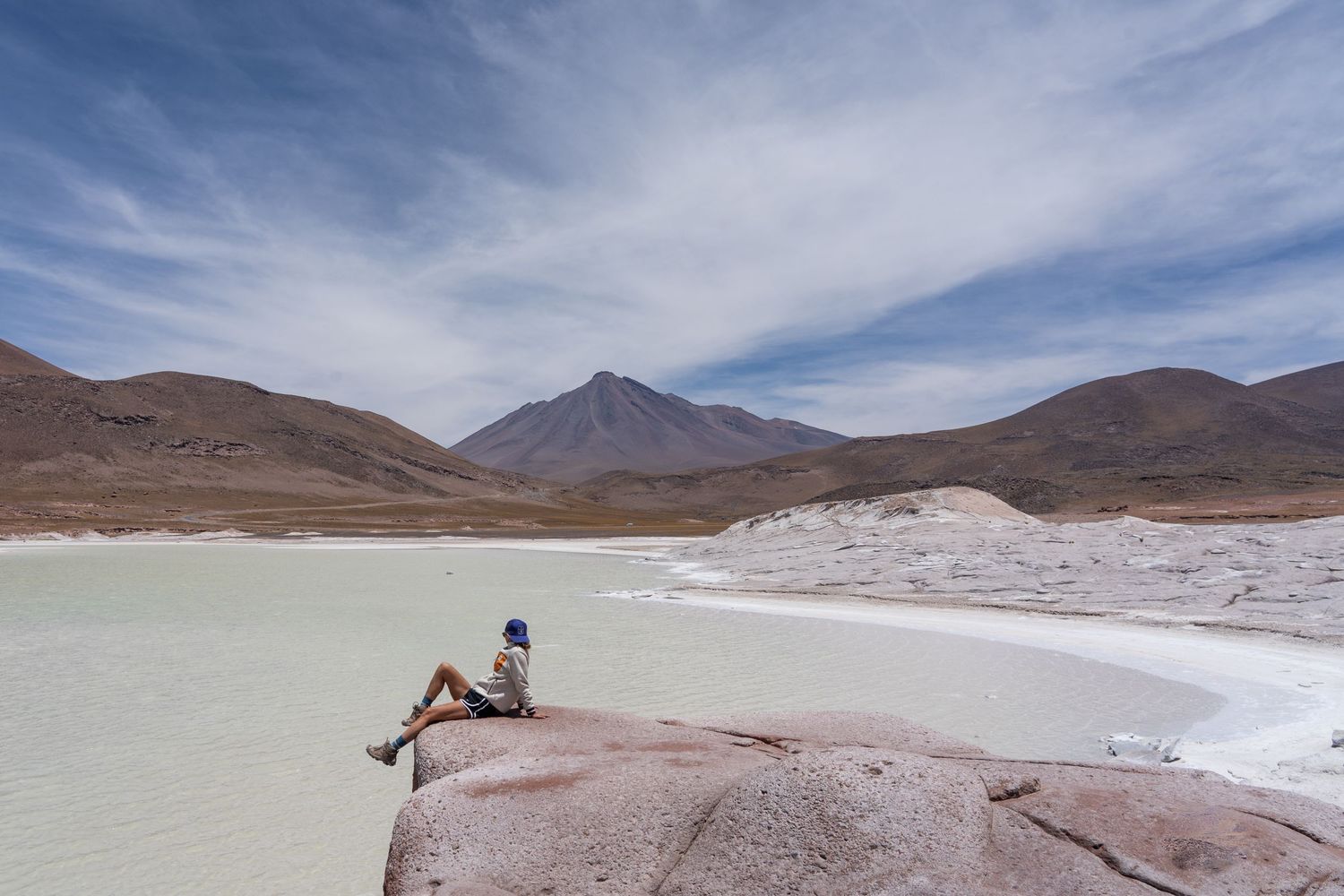 Madison the photographer from Mad Elopements, sits dangling her legs over the edge of a cliff with stunning views in San Pedro de Atacama.