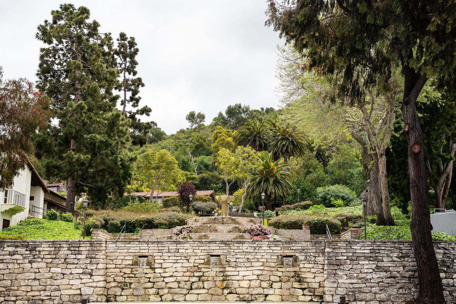The famous Malaga Cove fountain on a cloudy day. There are lots of trees and manicured lawns.