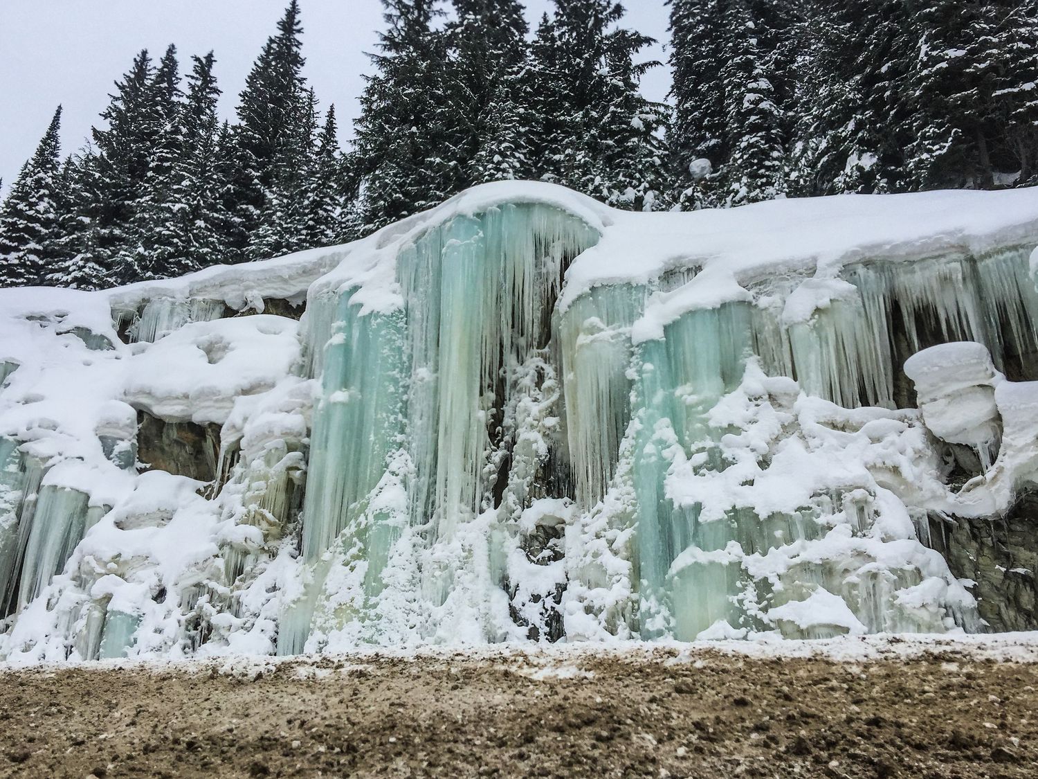 Rainbow ice falls cascade down the side of a mountain in Revelstoke, Canada. Driving home from a heli ski adventurous elopement.