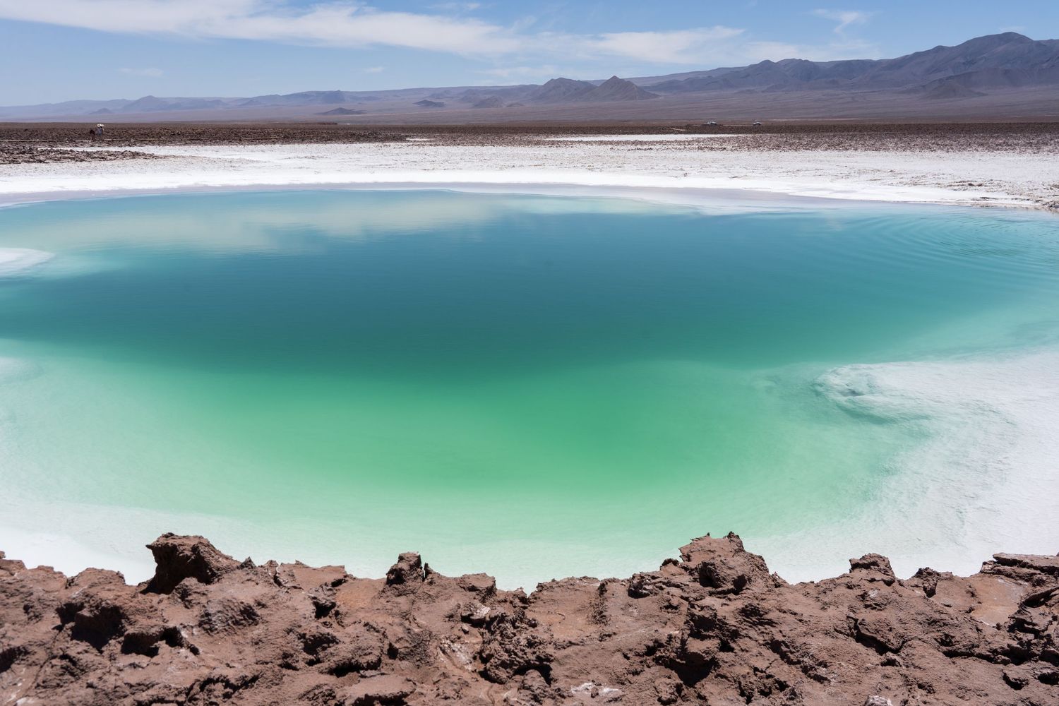 Vibrant green salt pool surrounded by volcanic rock outside of San Pedro de Atacama, Chile. A great place for a destination wedding.