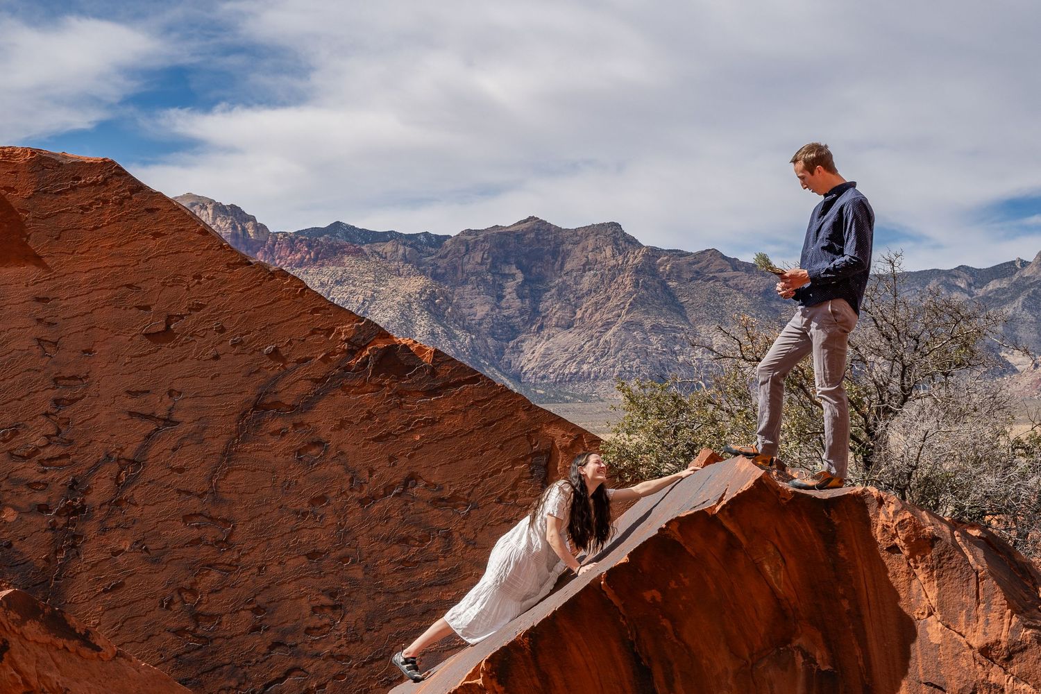 A couple climbing in Red Rocks Nevada in wedding clothes.