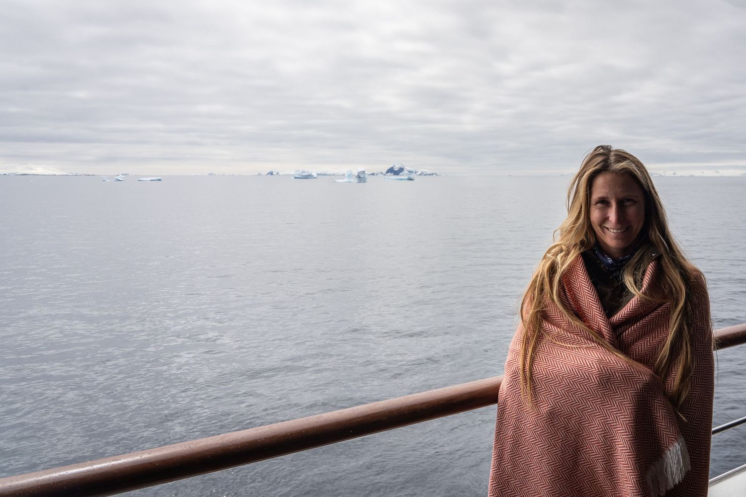 Madison from Mad Elopements on her luxury cruise ship private balcony sailing past icebergs in Antarctica.