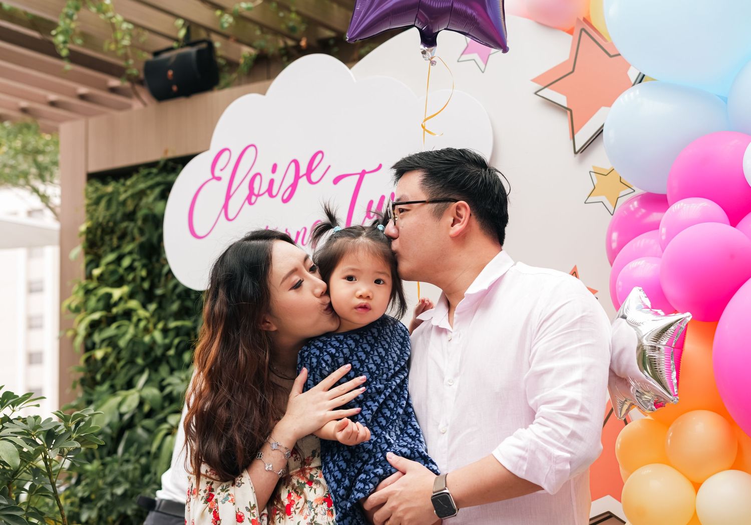 A family celebrates under decorative balloons and party decorations.