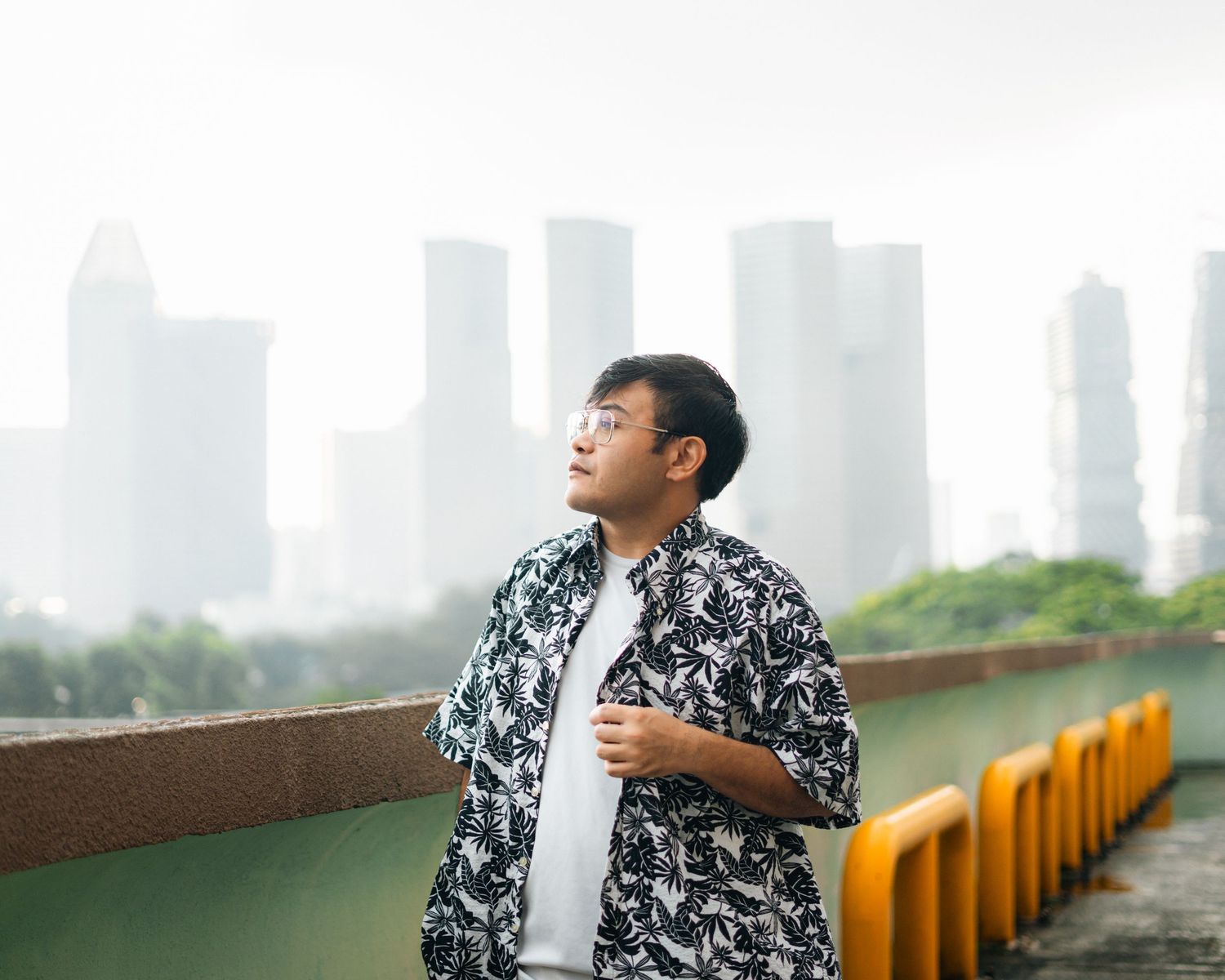A stylish portrait against a misty city skyline backdrop wearing a patterned shirt.
