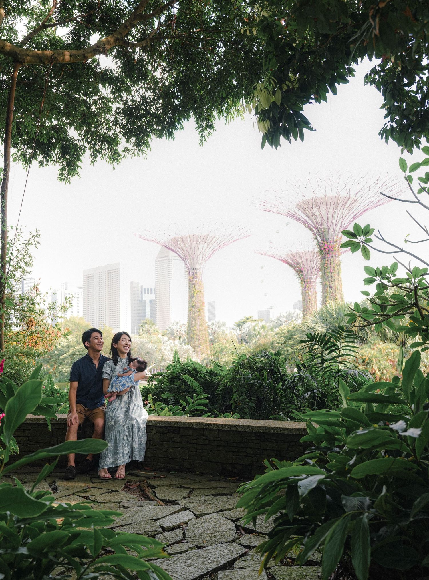 People enjoy a scenic garden path with Singapore's iconic Supertree Grove and city skyline visible in the background.