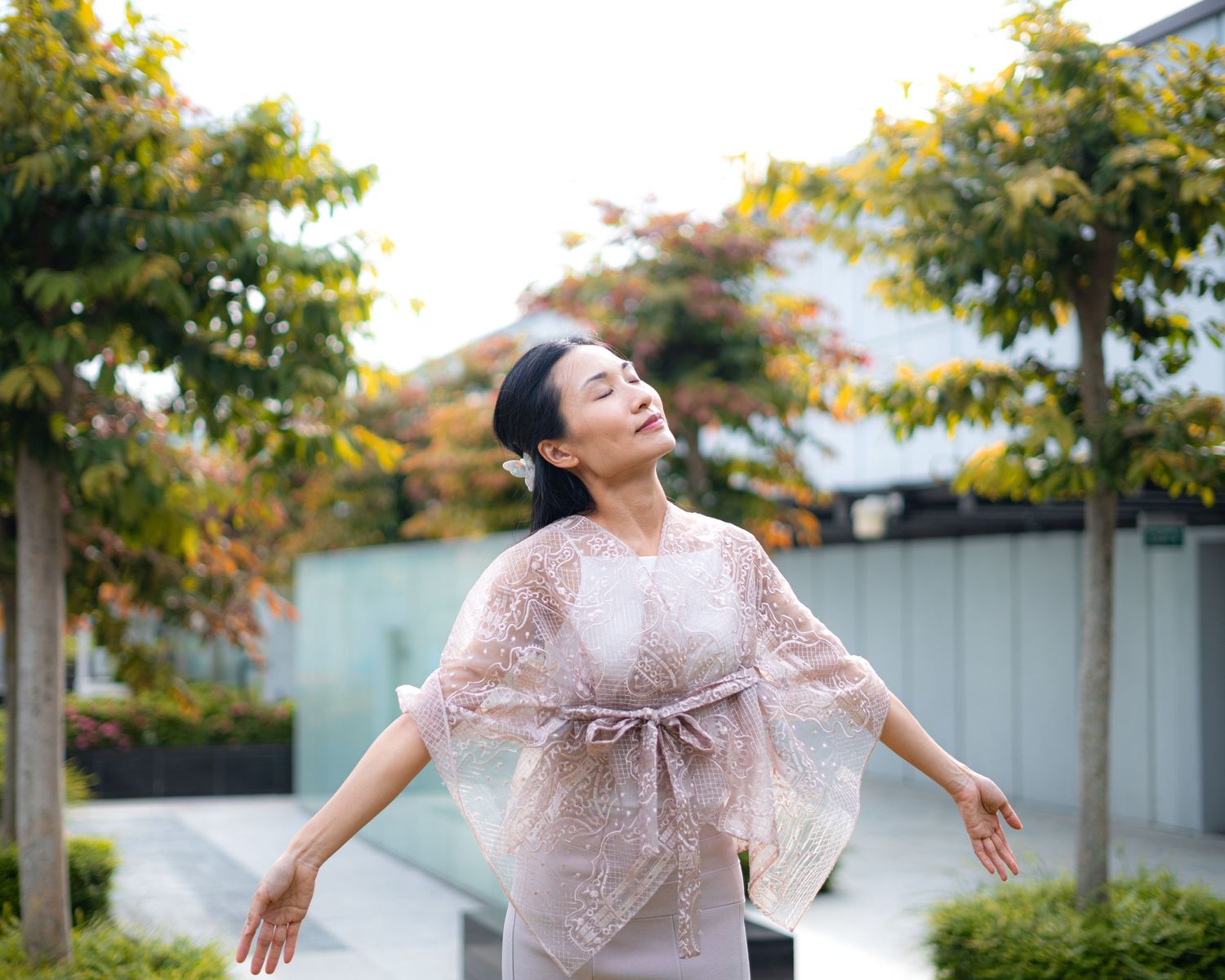 A flowing pink lace dress captures movement in an outdoor garden setting.