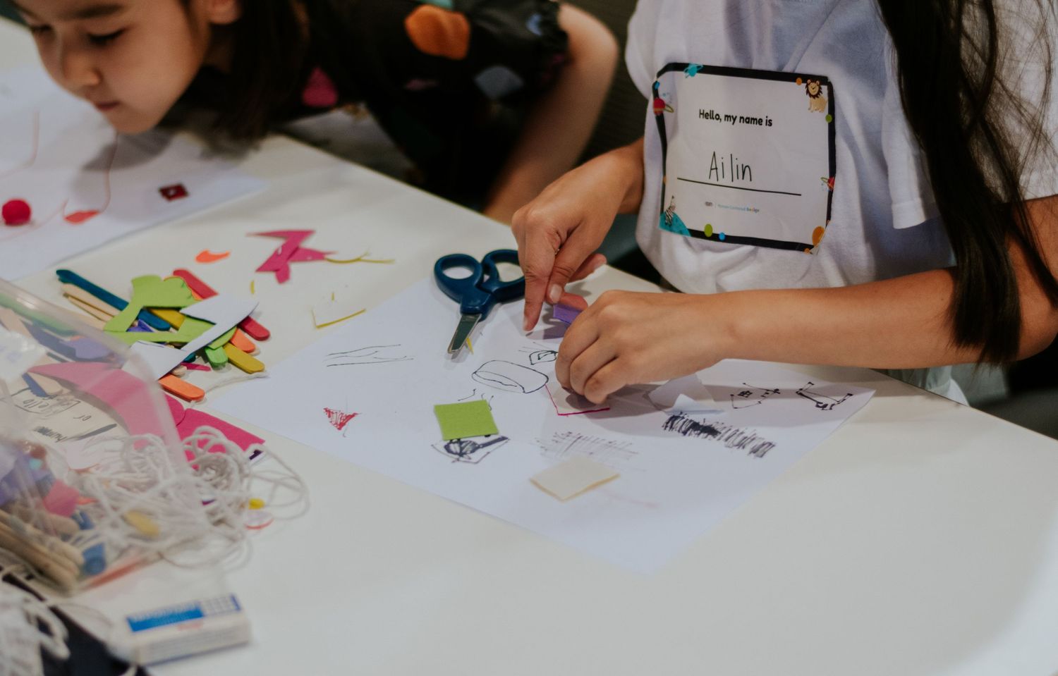 Students work together at tables on colorful art projects and creative activities during class time.