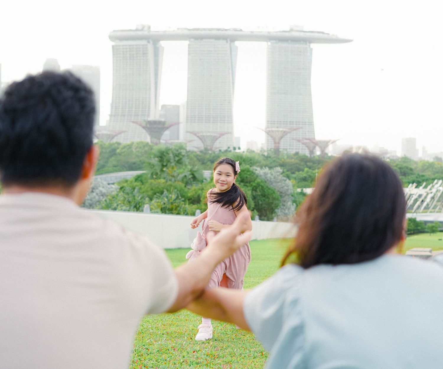 People enjoying a playful moment at Gardens by the Bay with Marina Bay Sands hotel visible in the background in Singapore.
