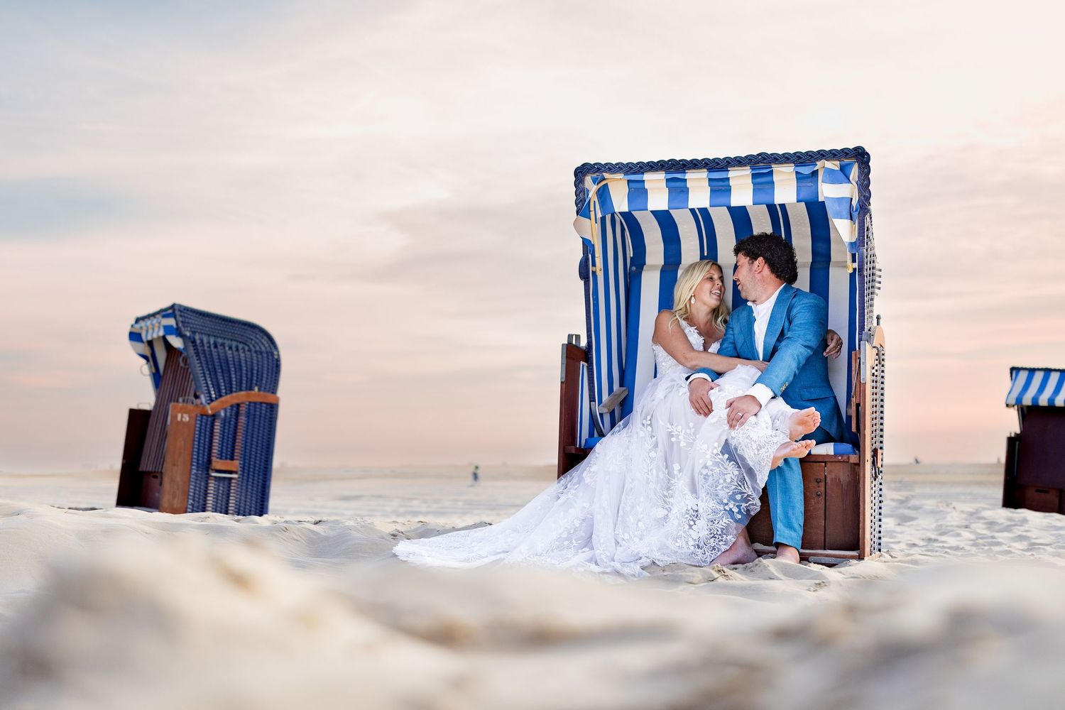 Bruid en bruidegom, in kleurrijke strandkorf. Romantisch tijdens ondergaande zon.