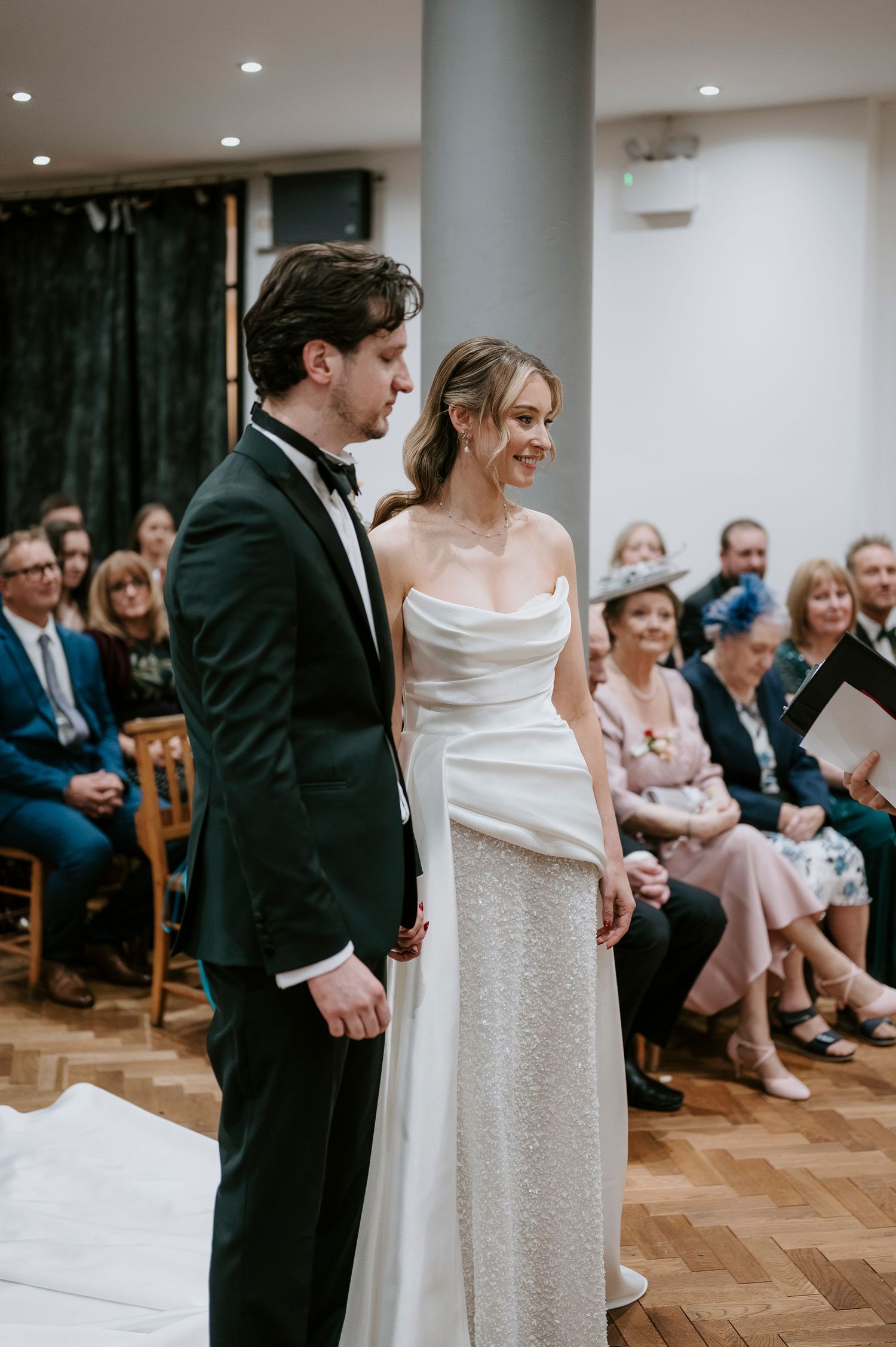 A couple performs a playful dance move at their wedding reception with guests watching in the background.