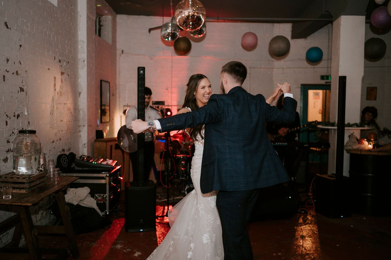 Bride and groom sharing romantic first dance with live band performing in background.