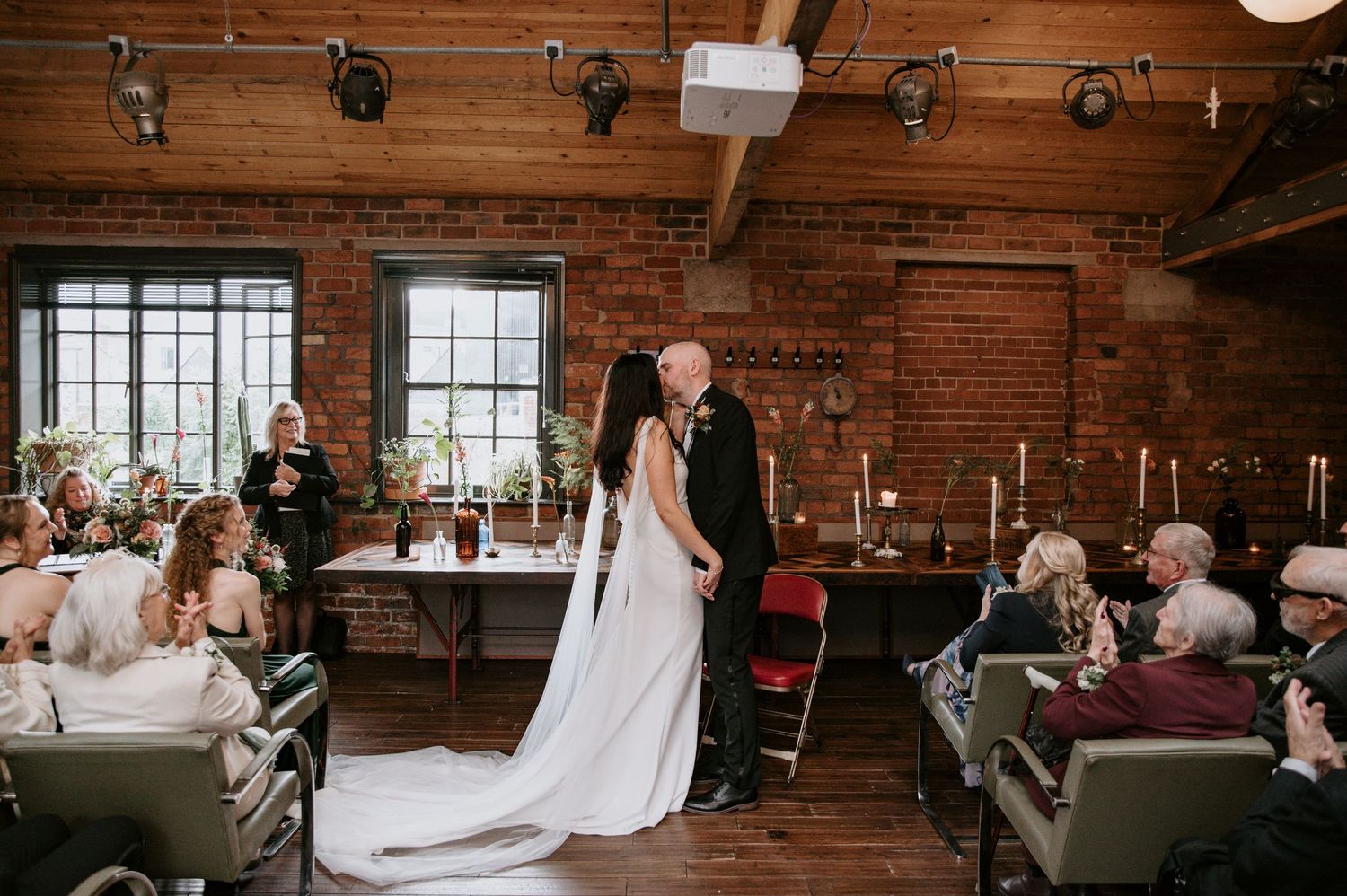 Elegant wedding ceremony setup in a rustic indoor venue with exposed brick walls and wooden beams.