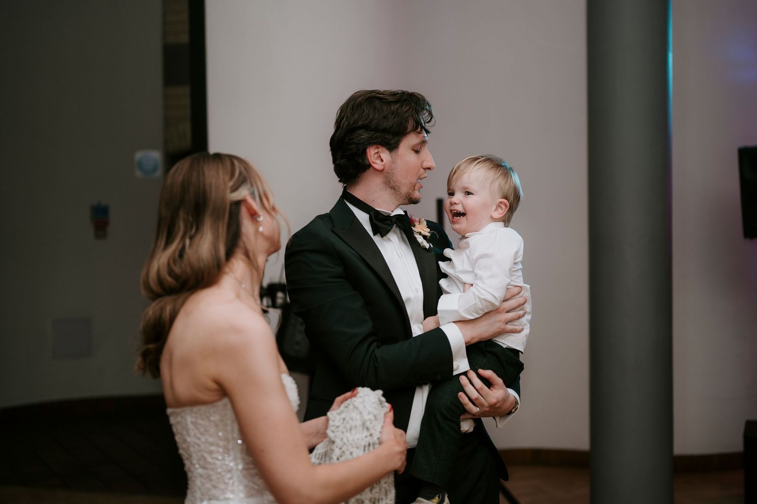 A sweet candid moment shared during a wedding reception with formal attire and laughter.