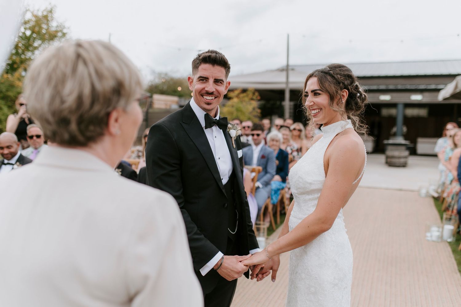 A couple exchanges vows during their outdoor wedding ceremony as guests look on from the courtyard.