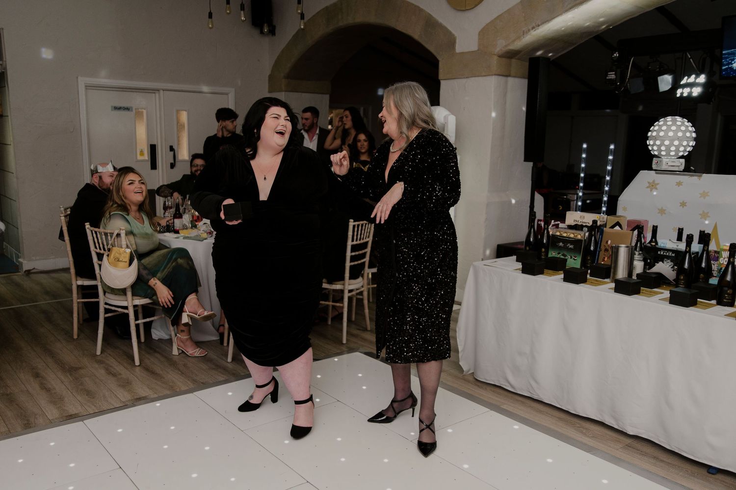 A group of people mingling and socializing at an elegant indoor event with white decor and formal attire.