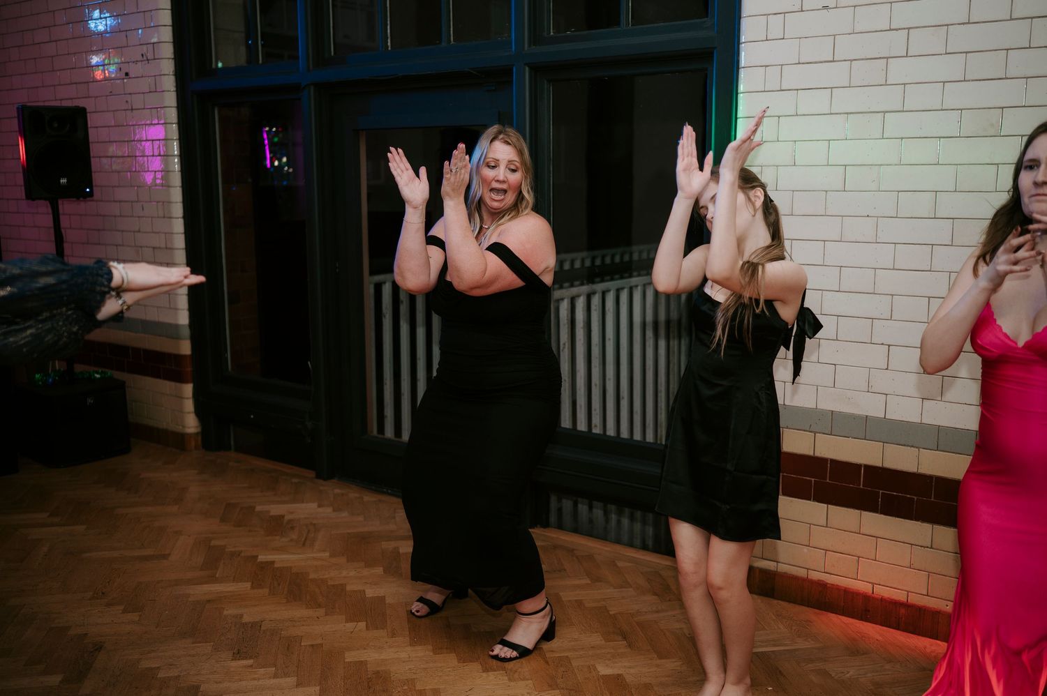 Wedding guests enjoying themselves on the dance floor under ambient lighting.