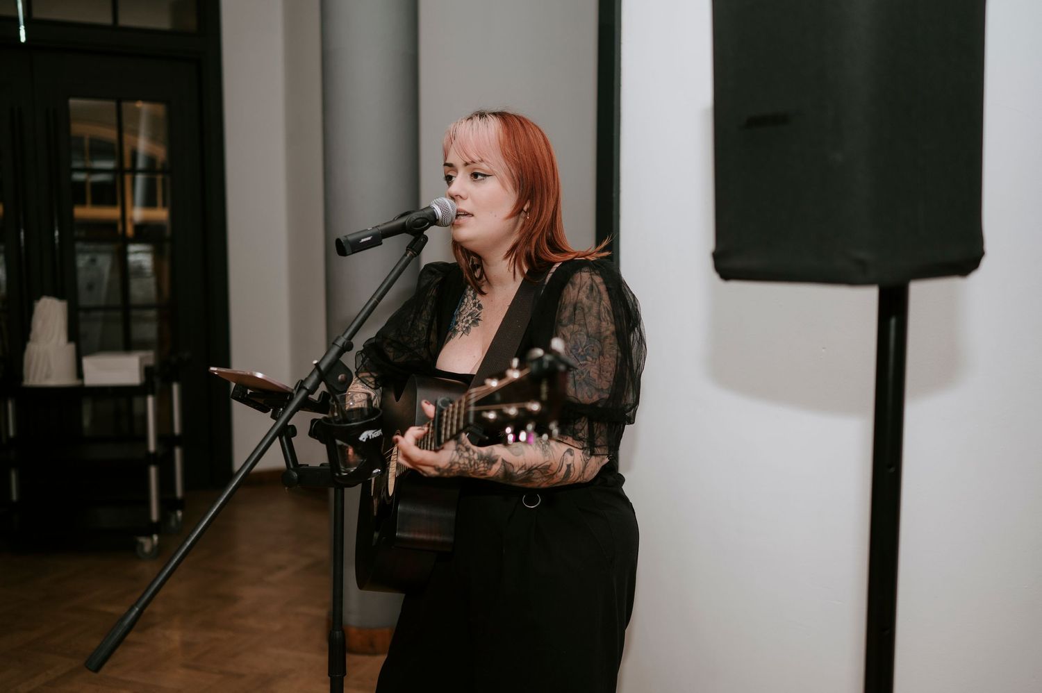 Musician performs at wedding reception with microphone and equipment setup.